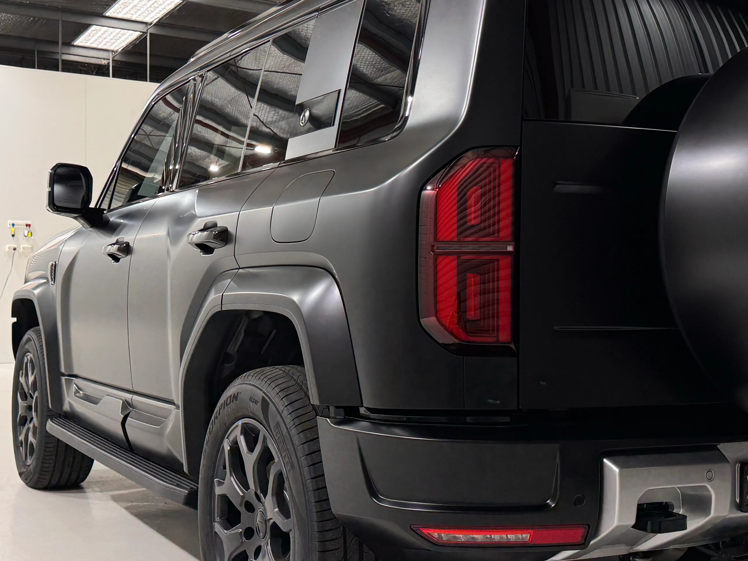 Low view along the satin grey Denza B5 side panels towards its rear light
