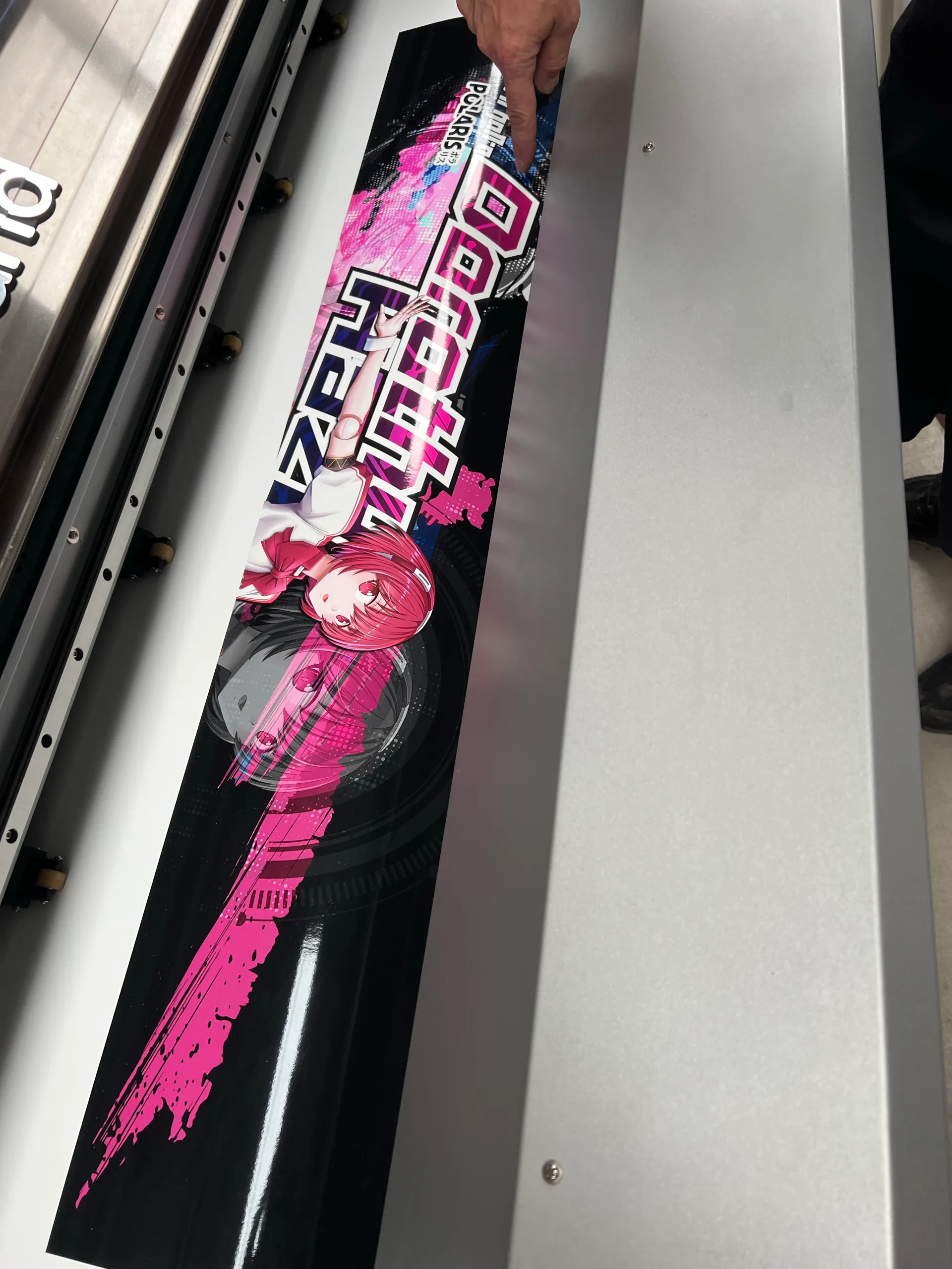 Gloved hand feeding anime printed film across the workshop table