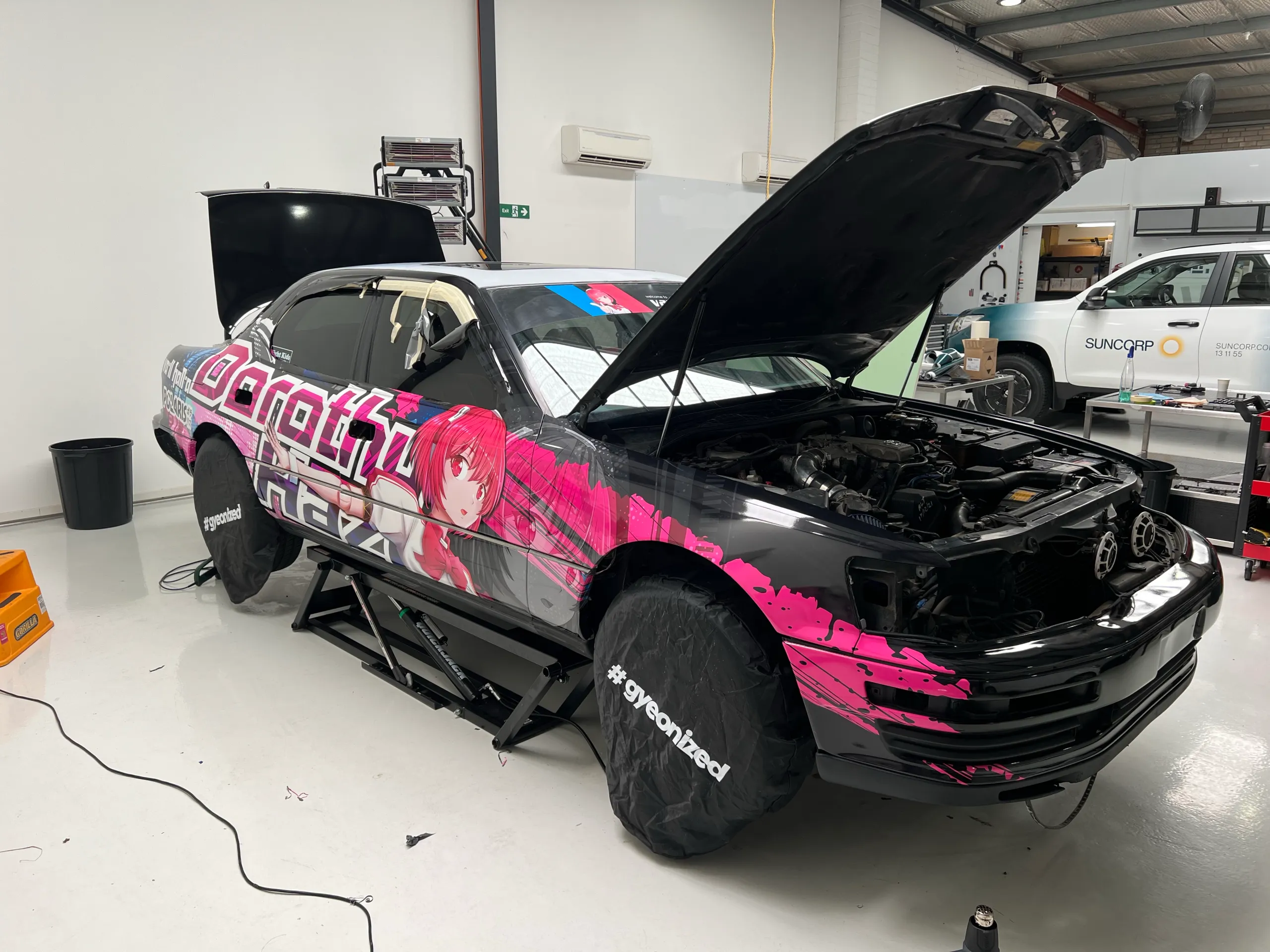 Toyota with its bonnet open during black and pink wrap installation