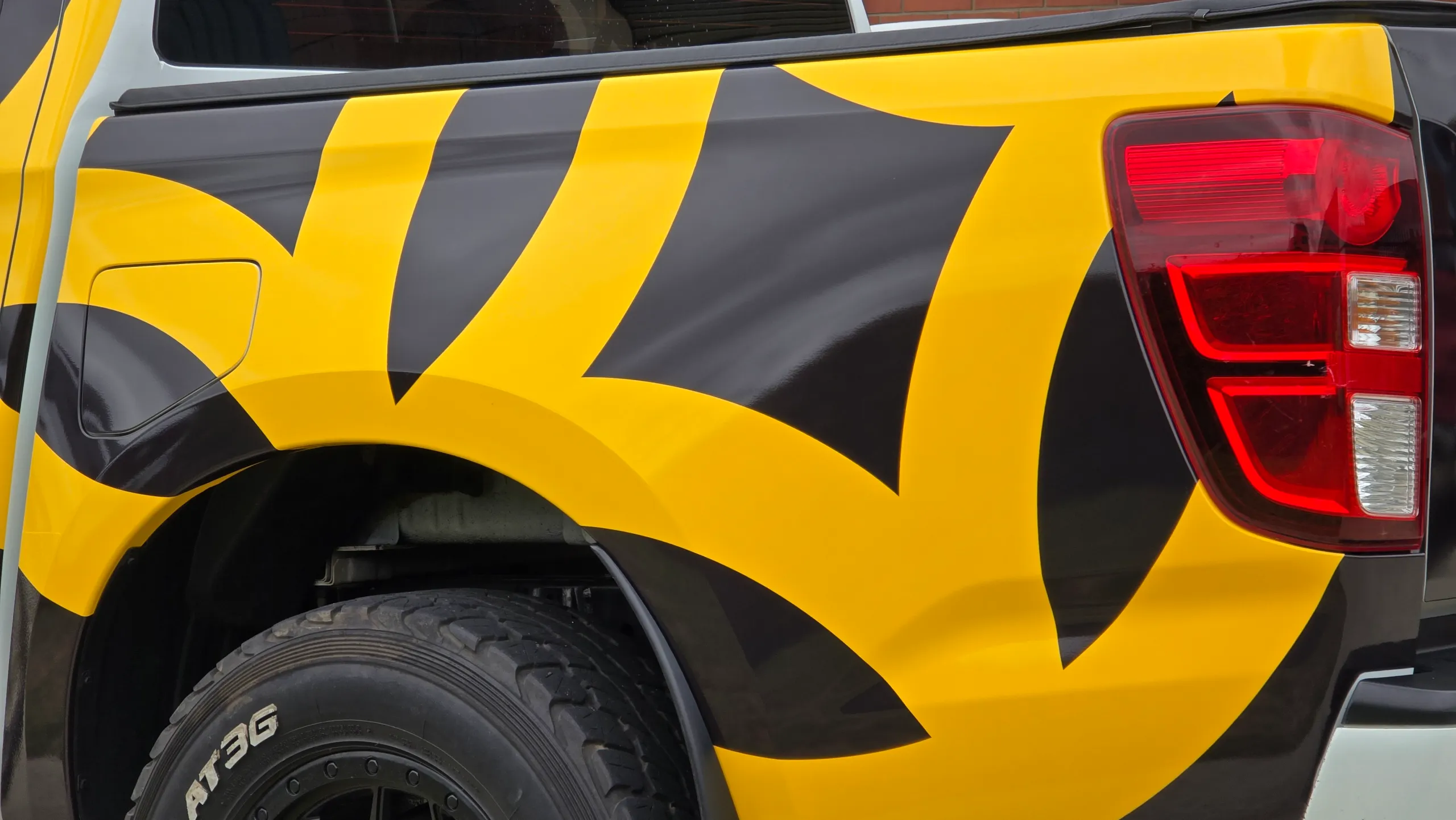 Yellow and black graphics around the Mazda BT-50 rear wheel arch and tail light