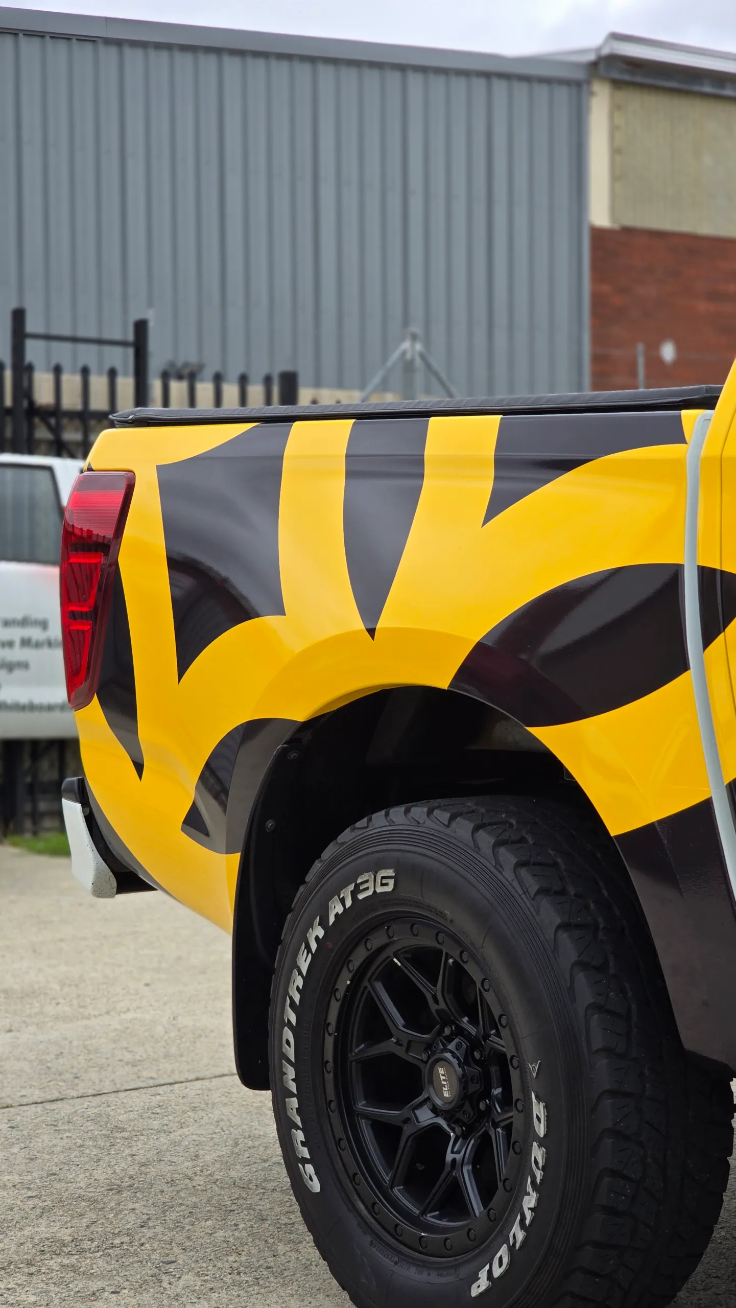 Black wheel beneath the Mazda BT-50 yellow and black tray graphics