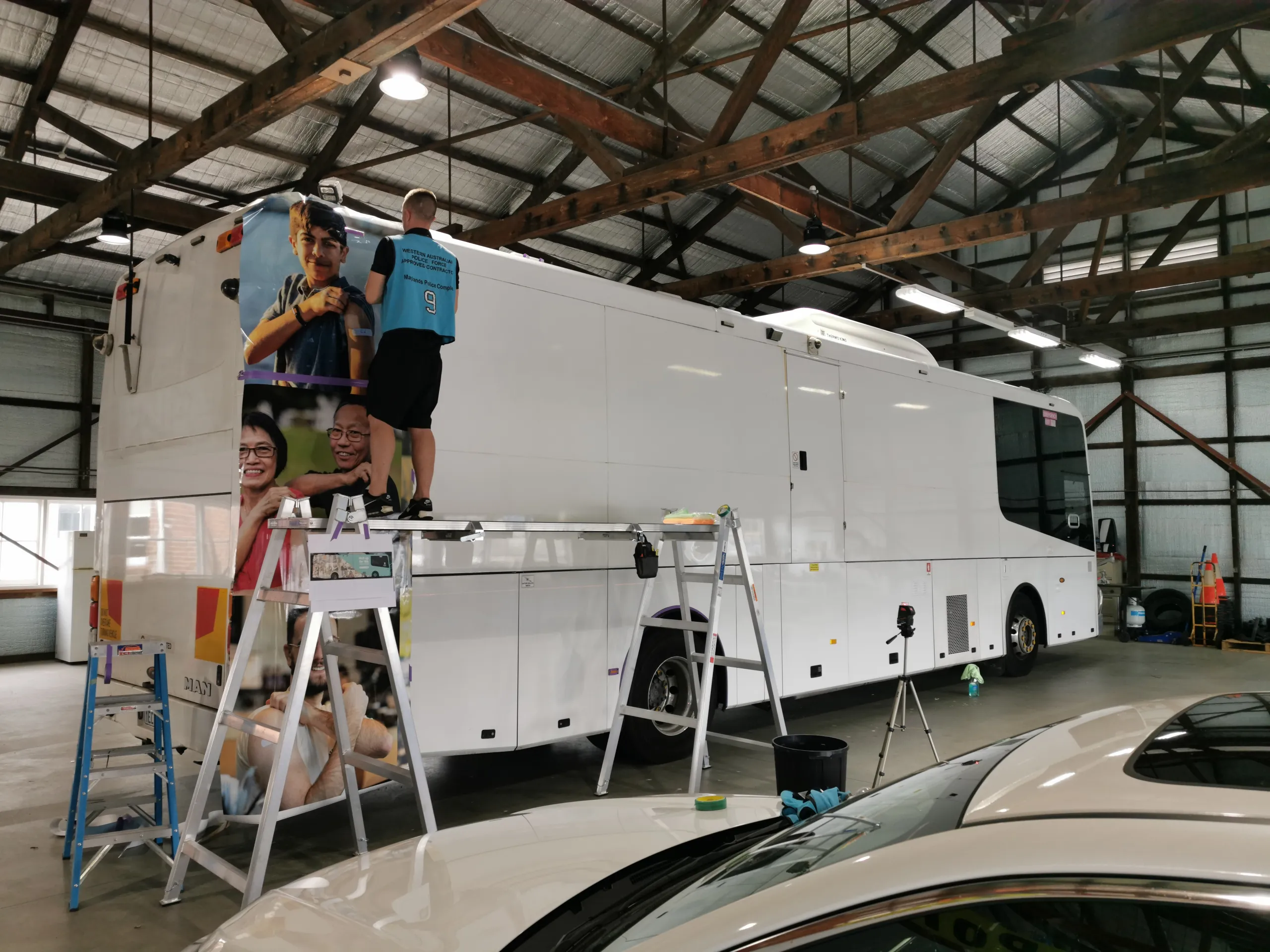 Installer on a ladder fitting printed film to the coach side