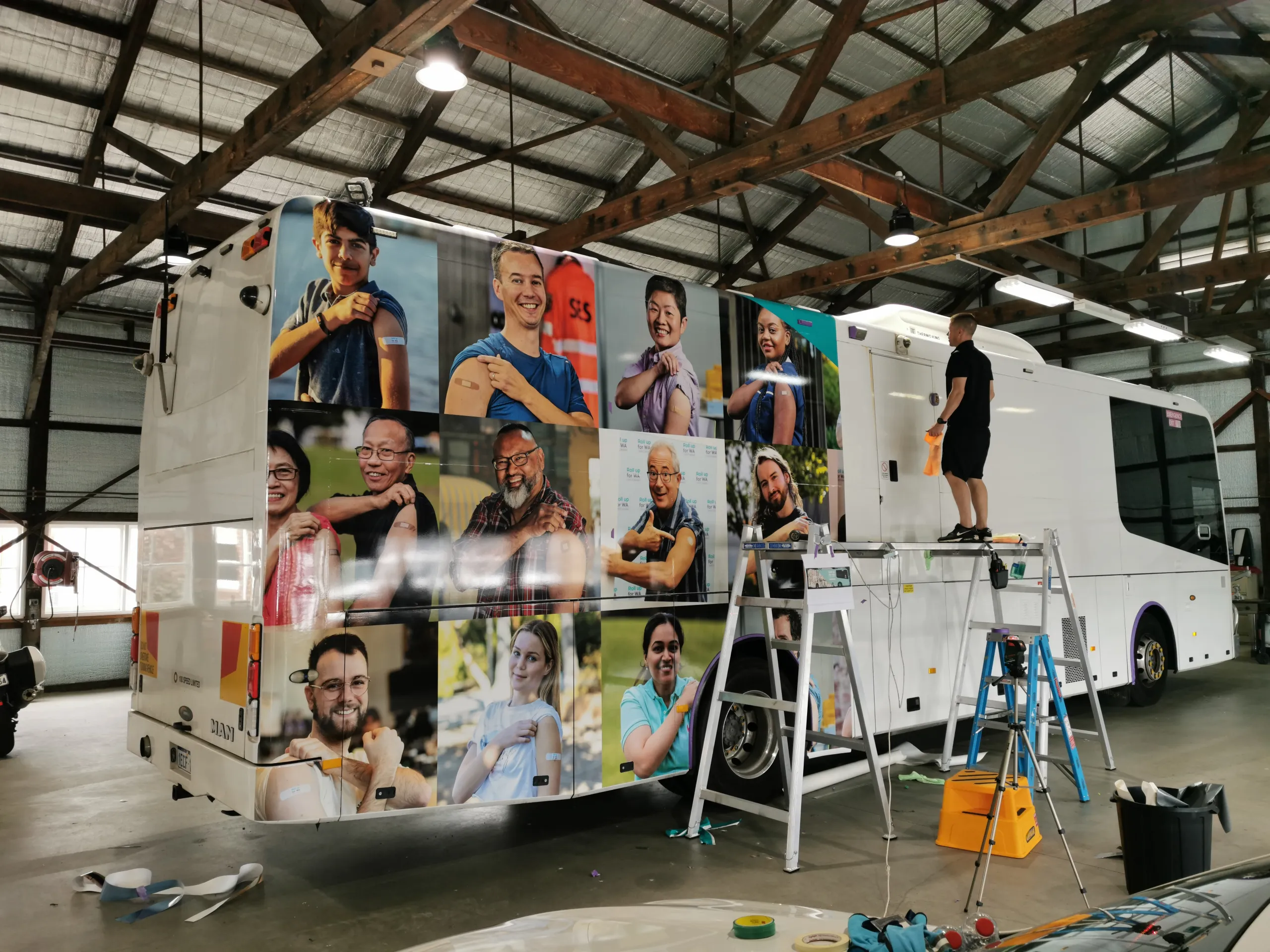 Installer fitting graphics to the coach from a ladder