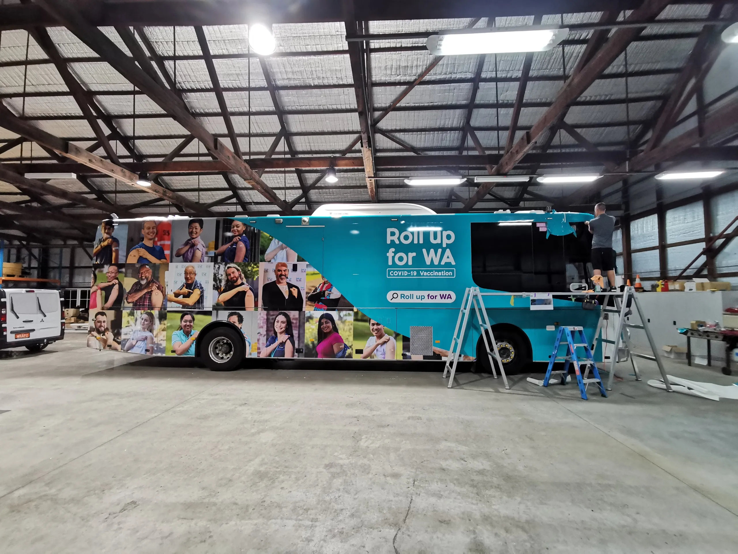 Installers fitting graphics around the front of the coach