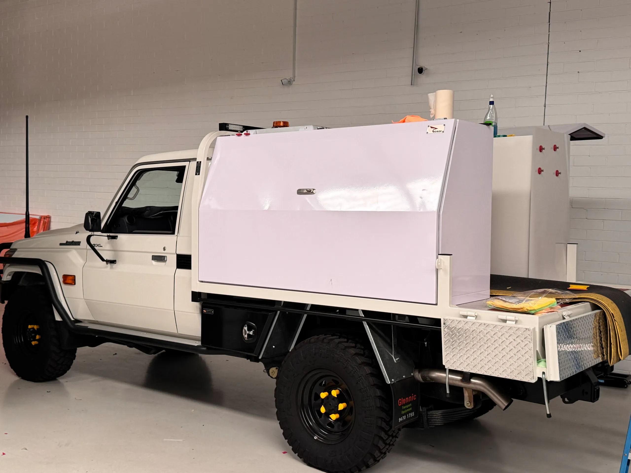 White LandCruiser with toolbox panels masked during preparation in the workshop