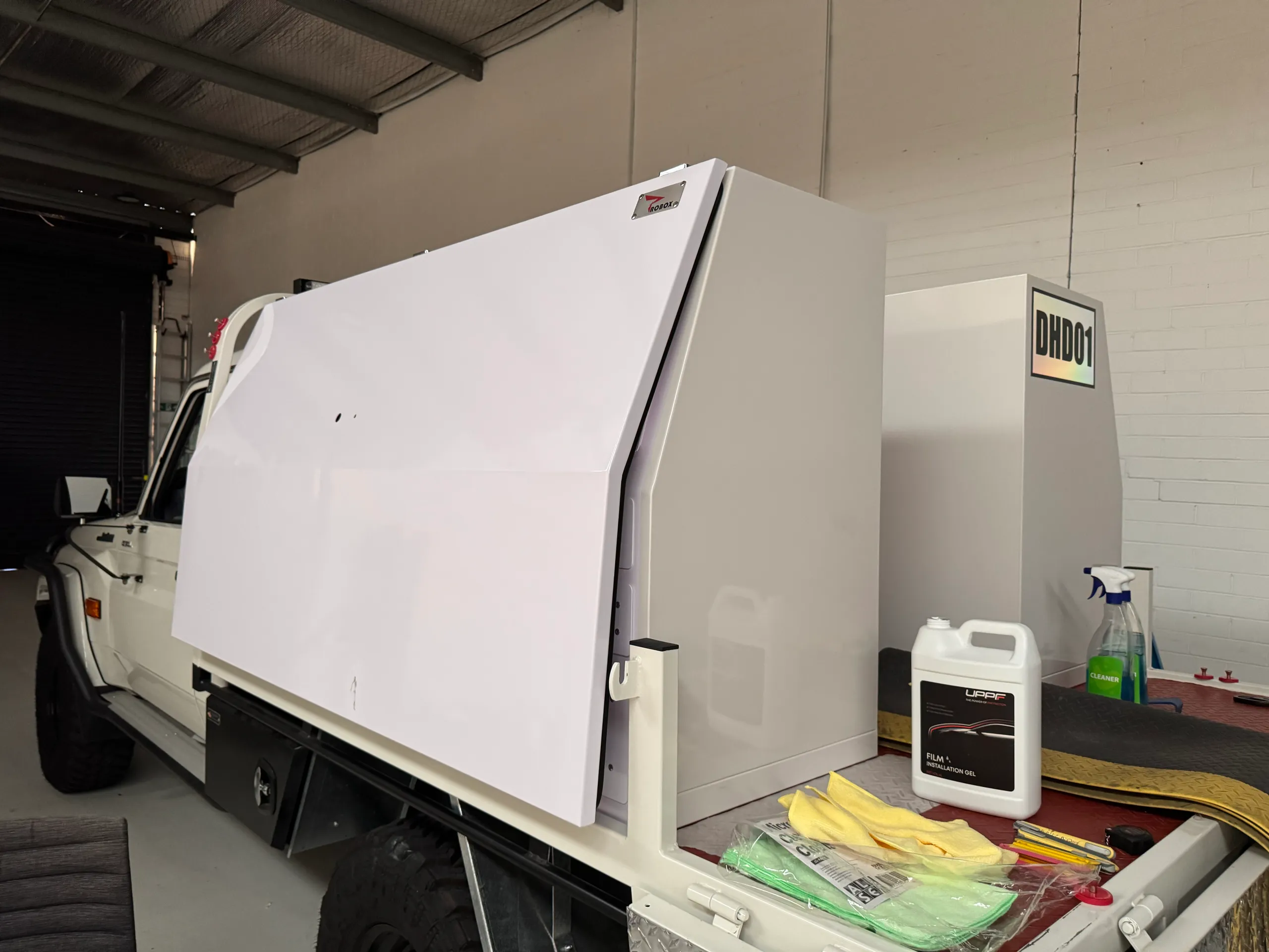 White LandCruiser toolbox panel with masking and installation supplies on the tray