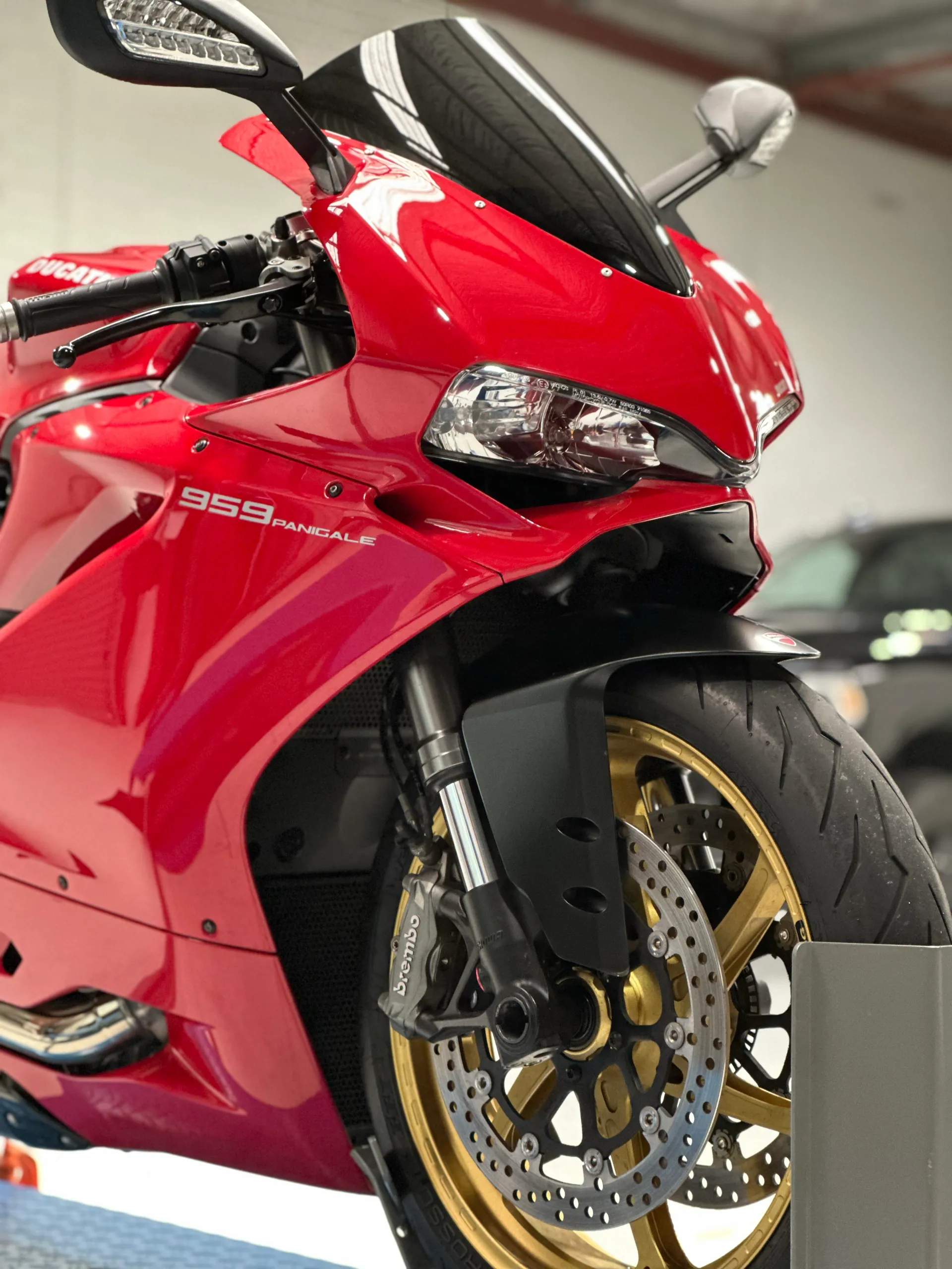 Red Ducati 959 Panigale front fairing, headlight and gold front wheel on a workshop lift
