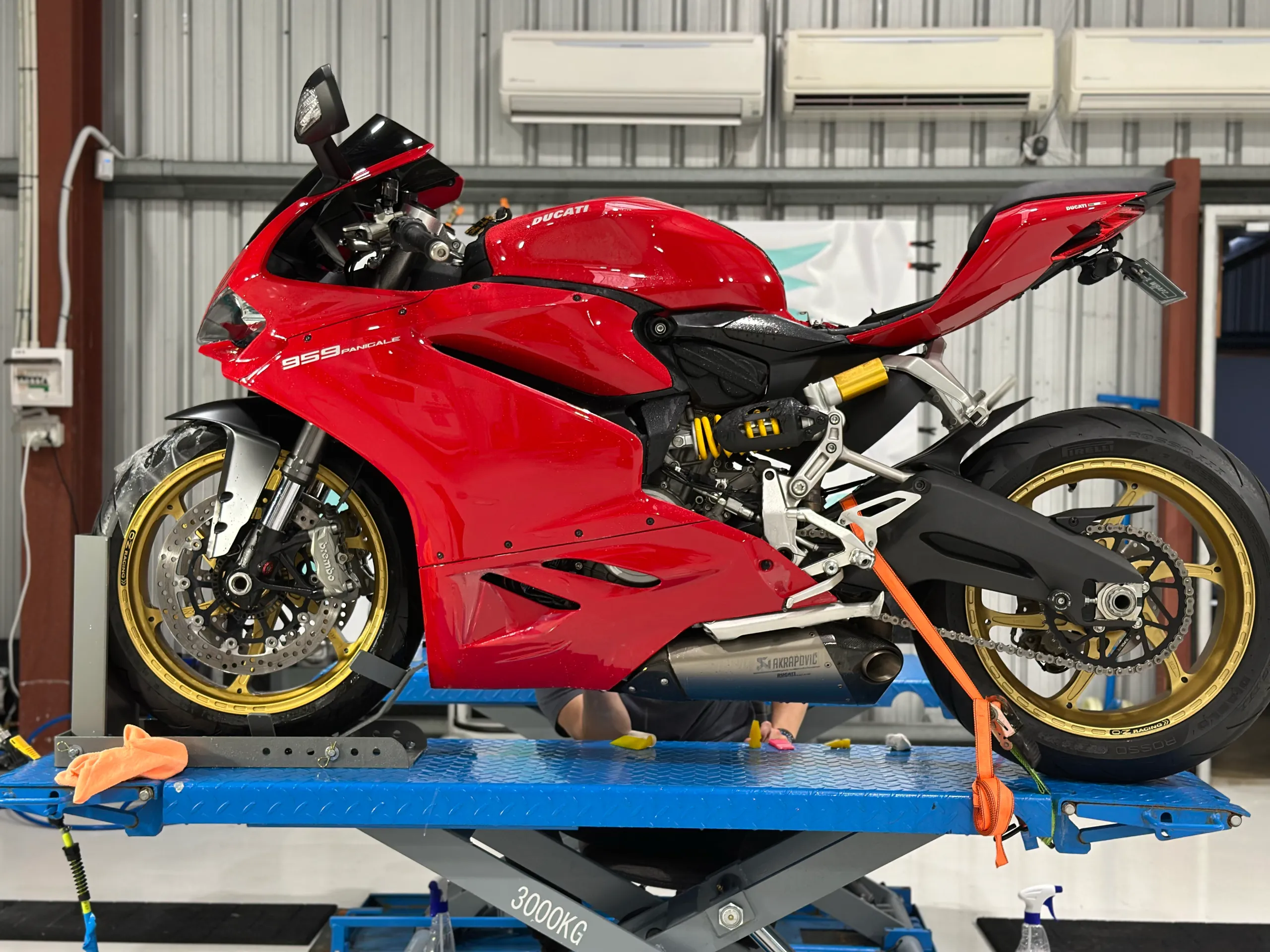 Red Ducati 959 Panigale in side profile on a workshop lift with its seat removed during work