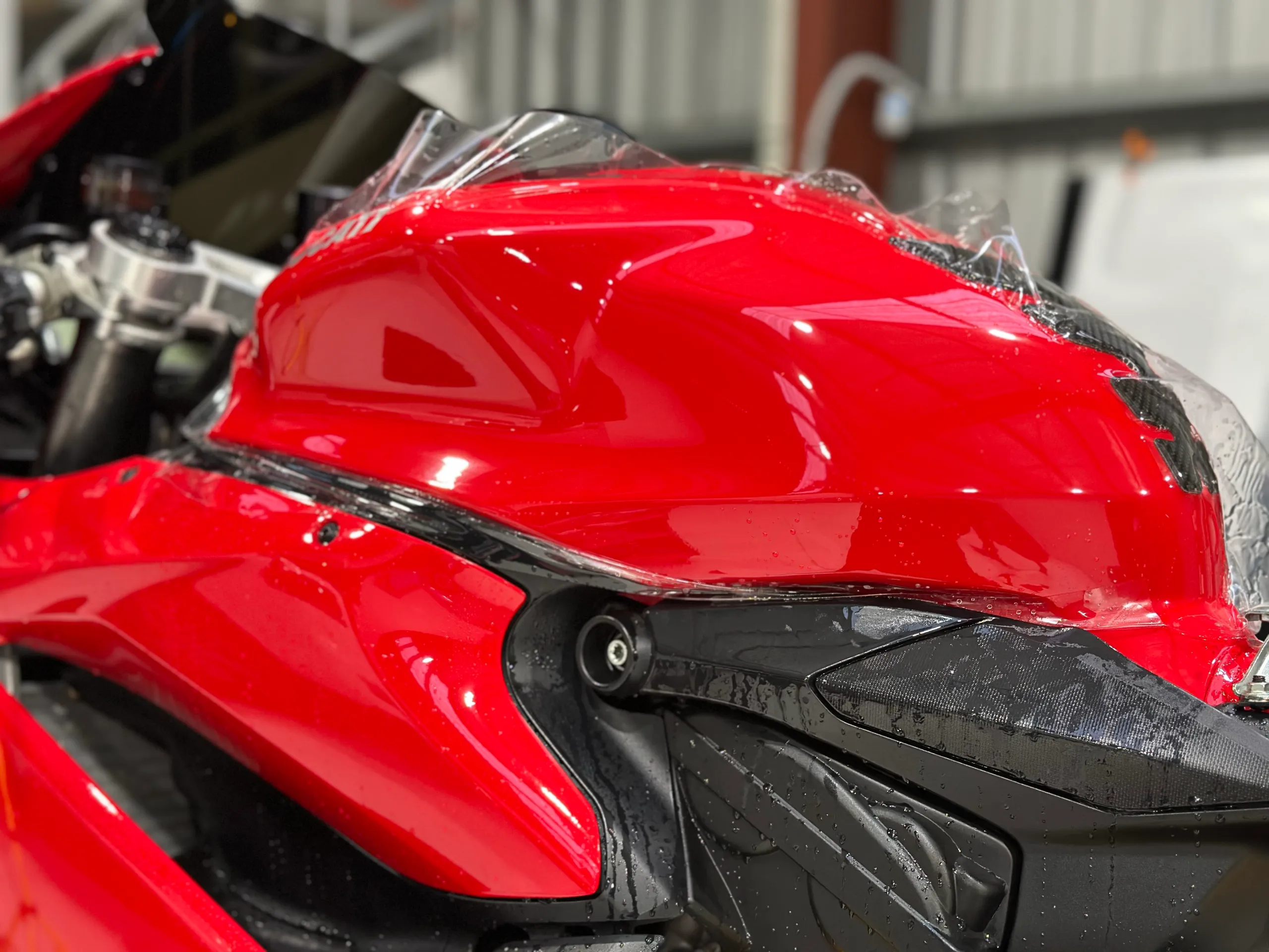 Clear film being fitted over the red fuel tank of a Ducati 959 Panigale