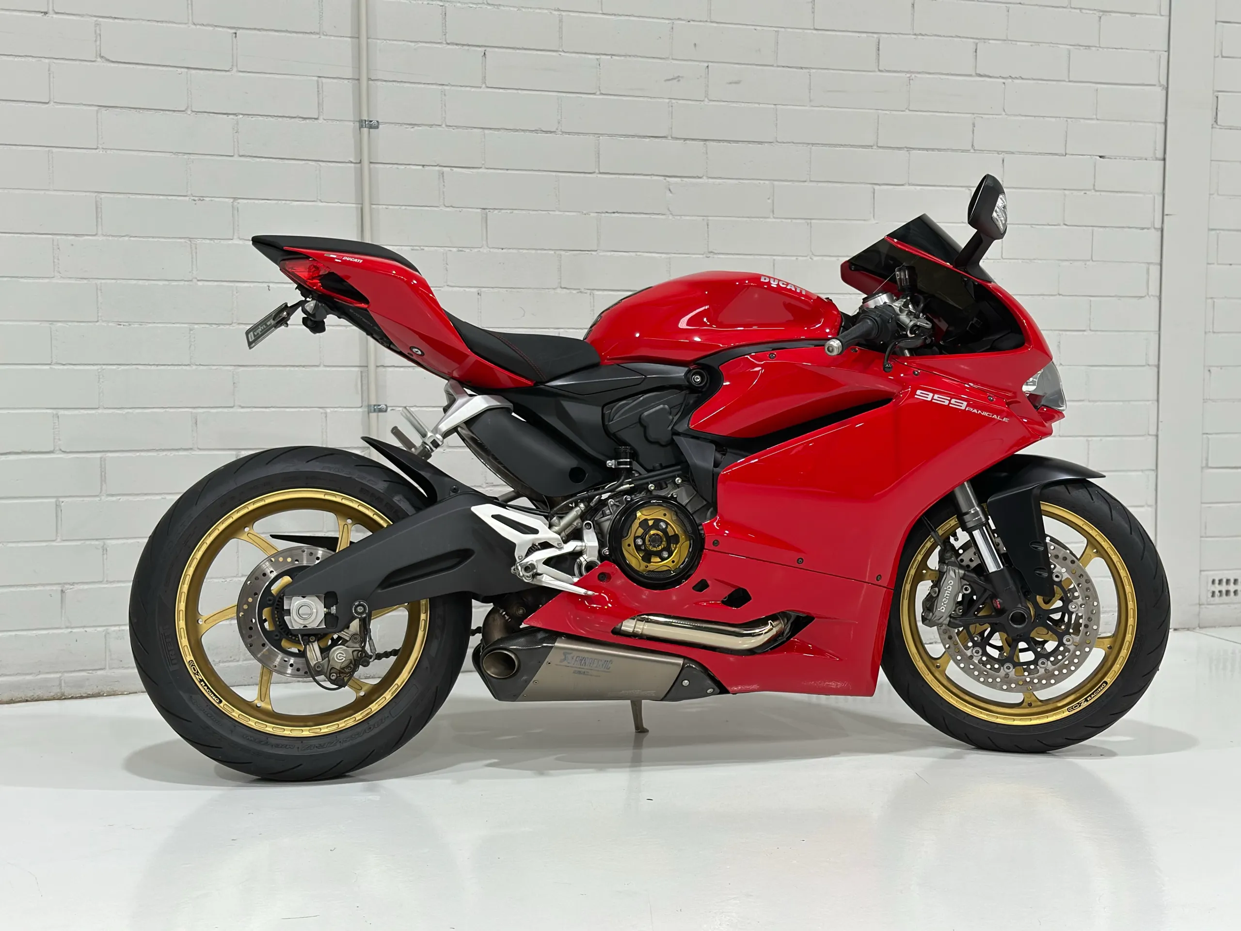 Red Ducati 959 Panigale in side profile with gold wheels and a black seat