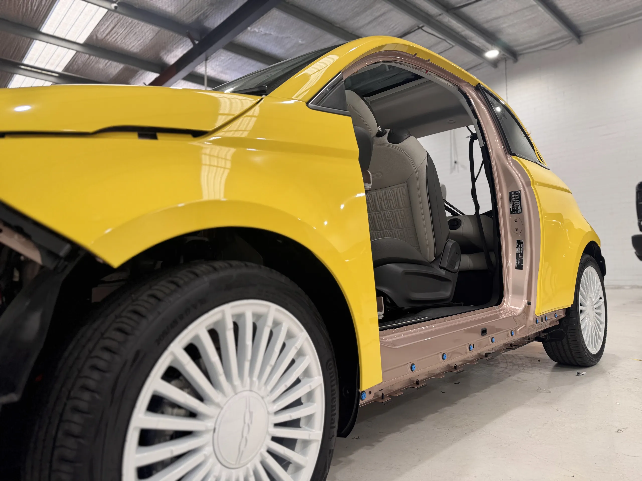 Low view of the Fiat 500 door opening with the door removed and yellow exterior panels fitted