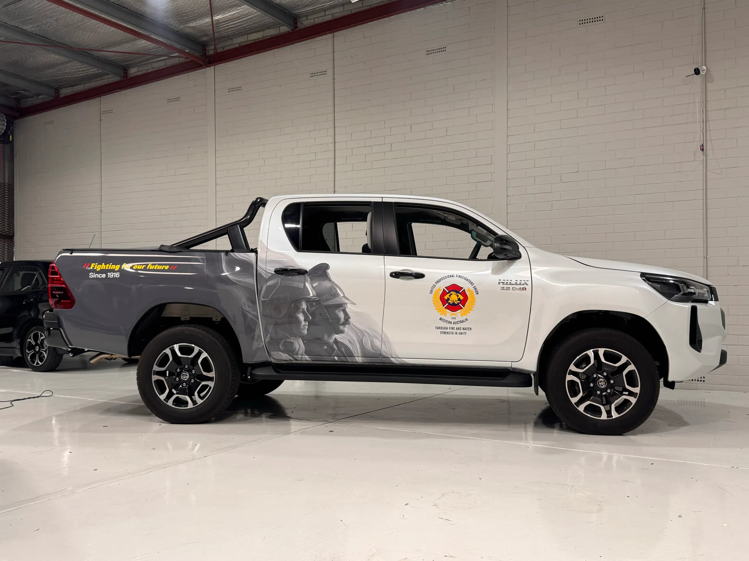 White Toyota Hilux with grey Firefighters Union graphics along its doors and tray