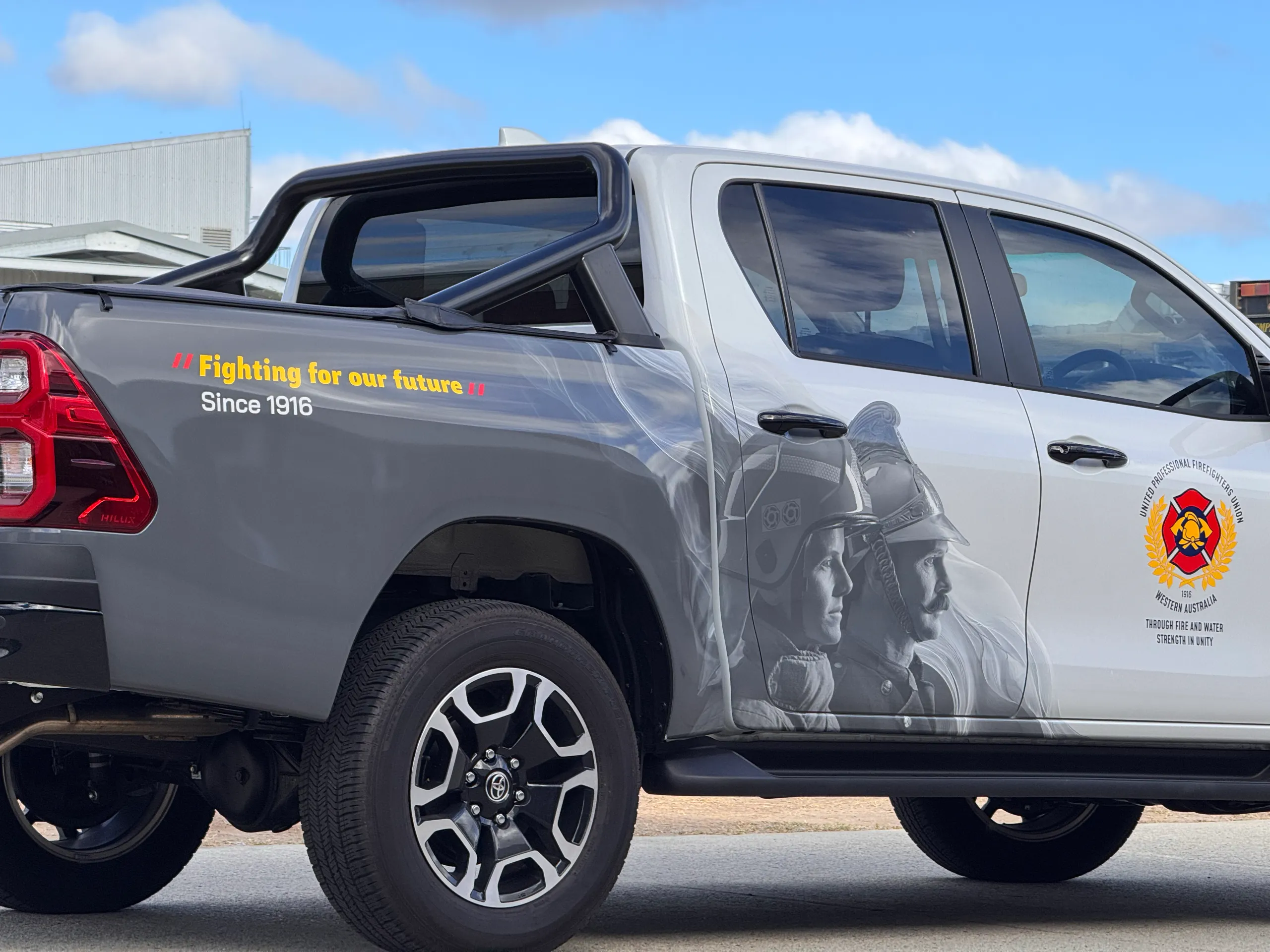 Firefighter portraits and yellow lettering across the Toyota Hilux rear quarter outdoors