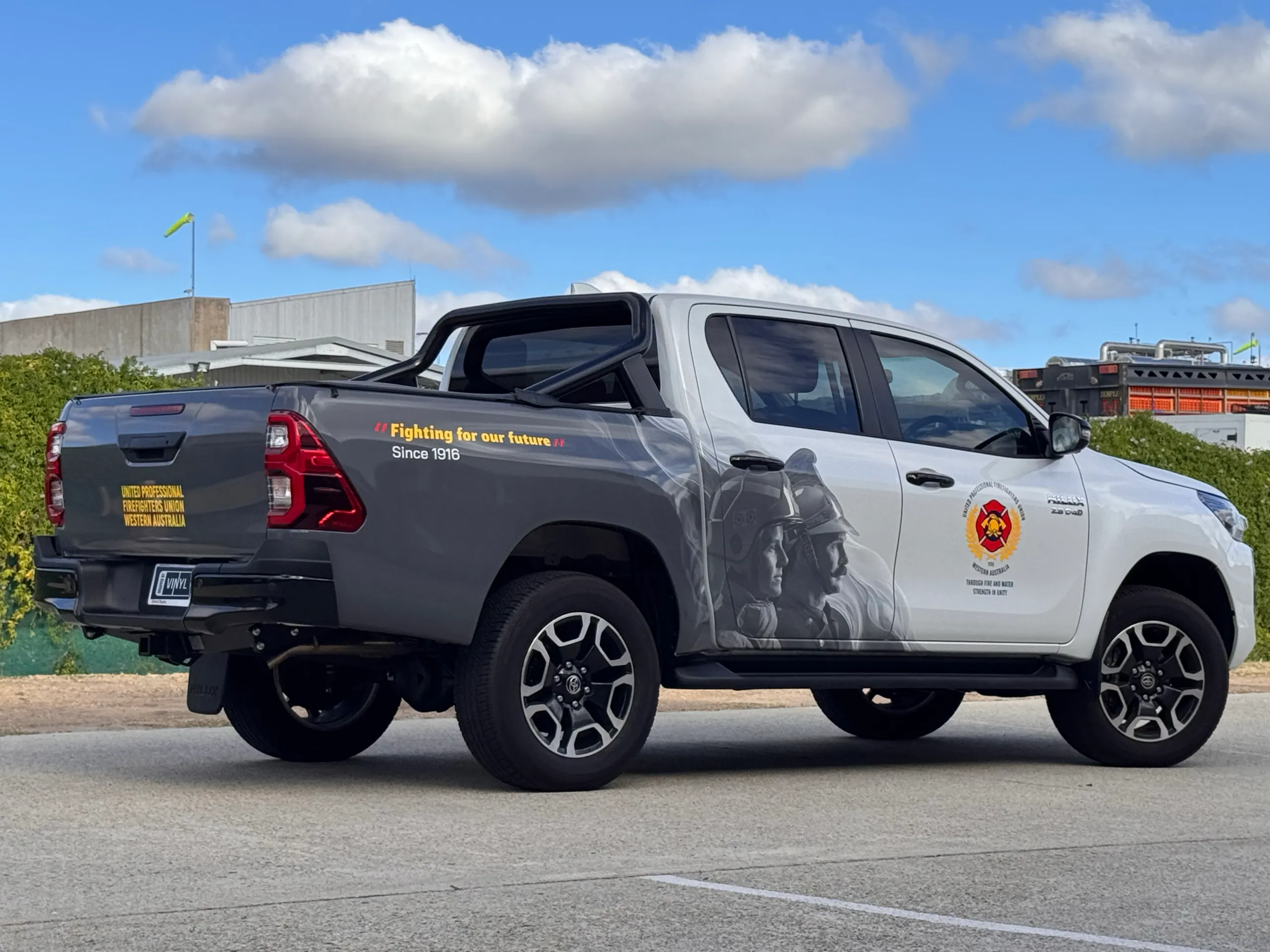 Toyota Hilux with Firefighters Union partial-wrap graphics outside the workshop