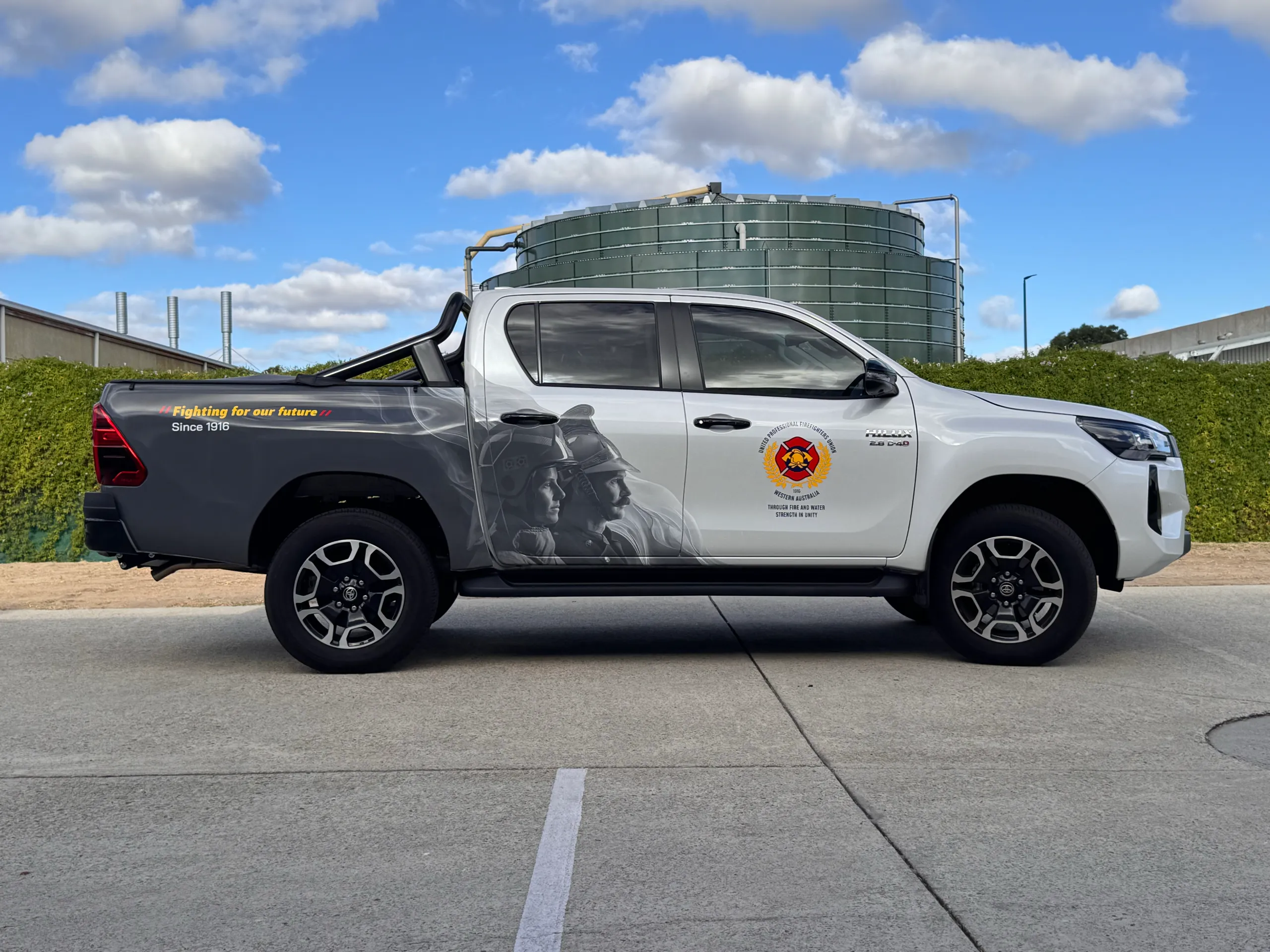 Side view of the white Toyota Hilux with firefighter artwork and union branding