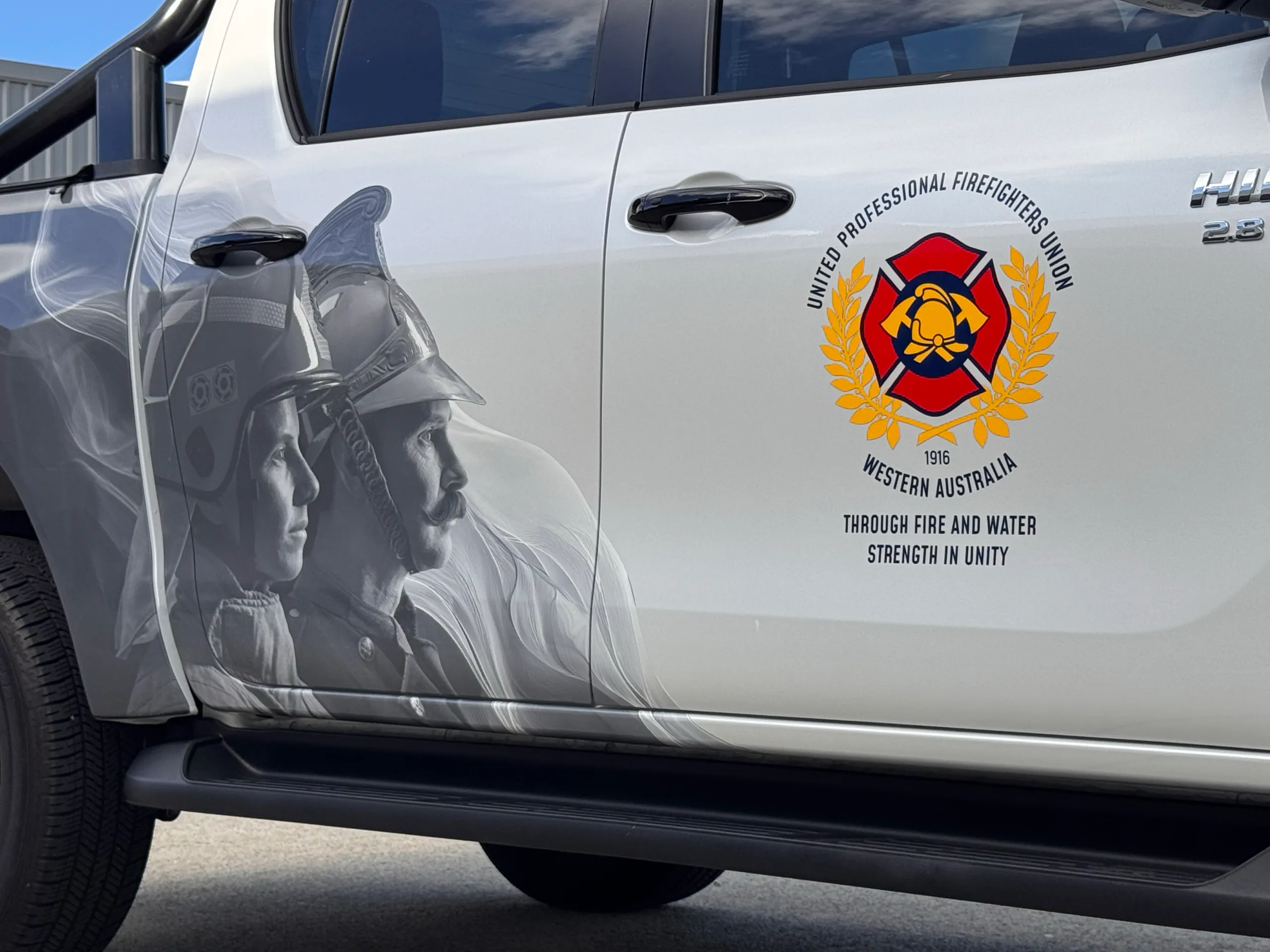 United Professional Firefighters Union Western Australia emblem beside firefighter artwork on the Hilux doors