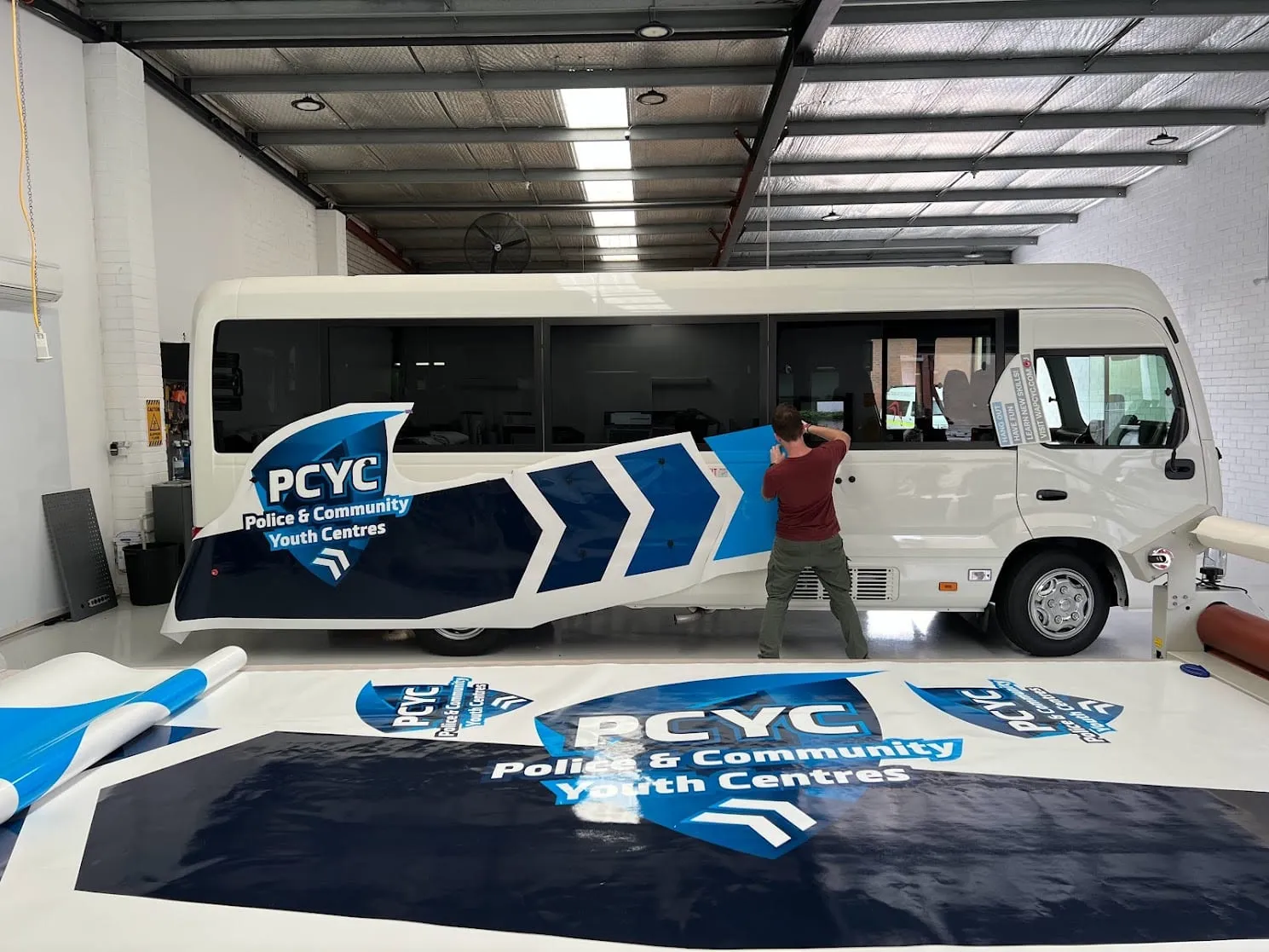 PCYC bus in the Vinyl Wrapz workshop with the printed graphics being applied
