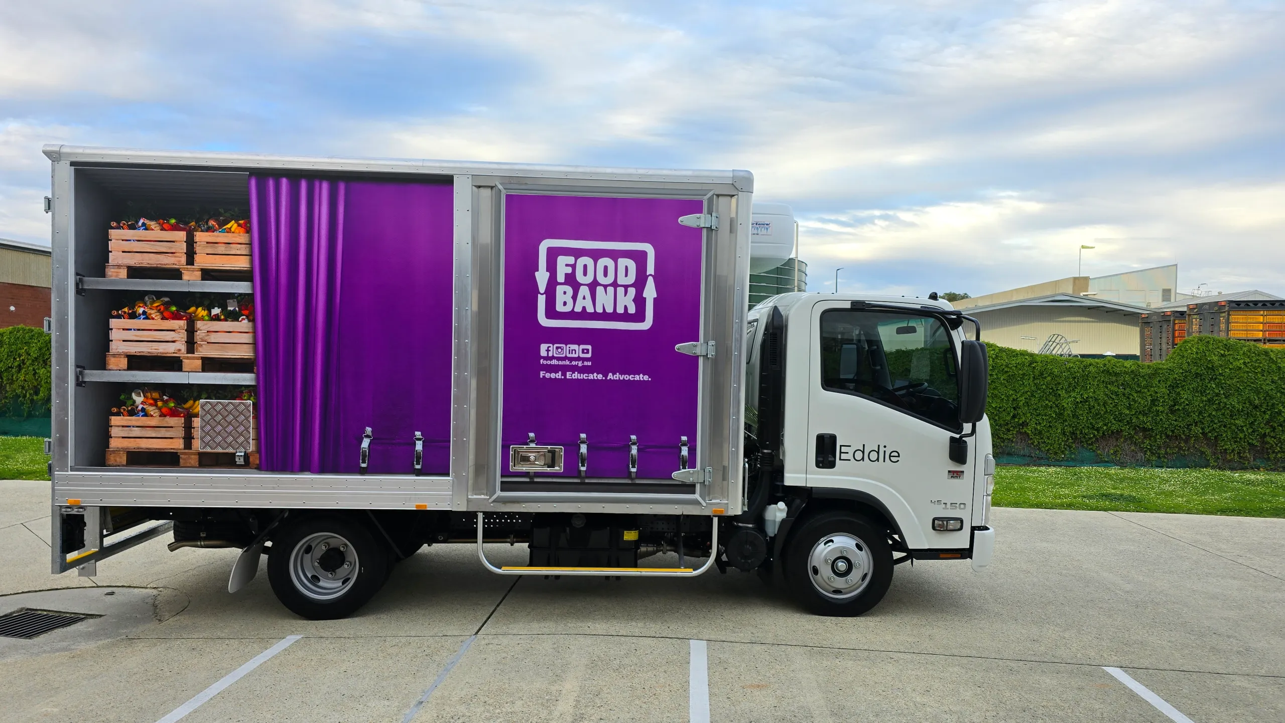 Foodbank refrigerated truck in side profile, with purple branding and printed shelves of produce