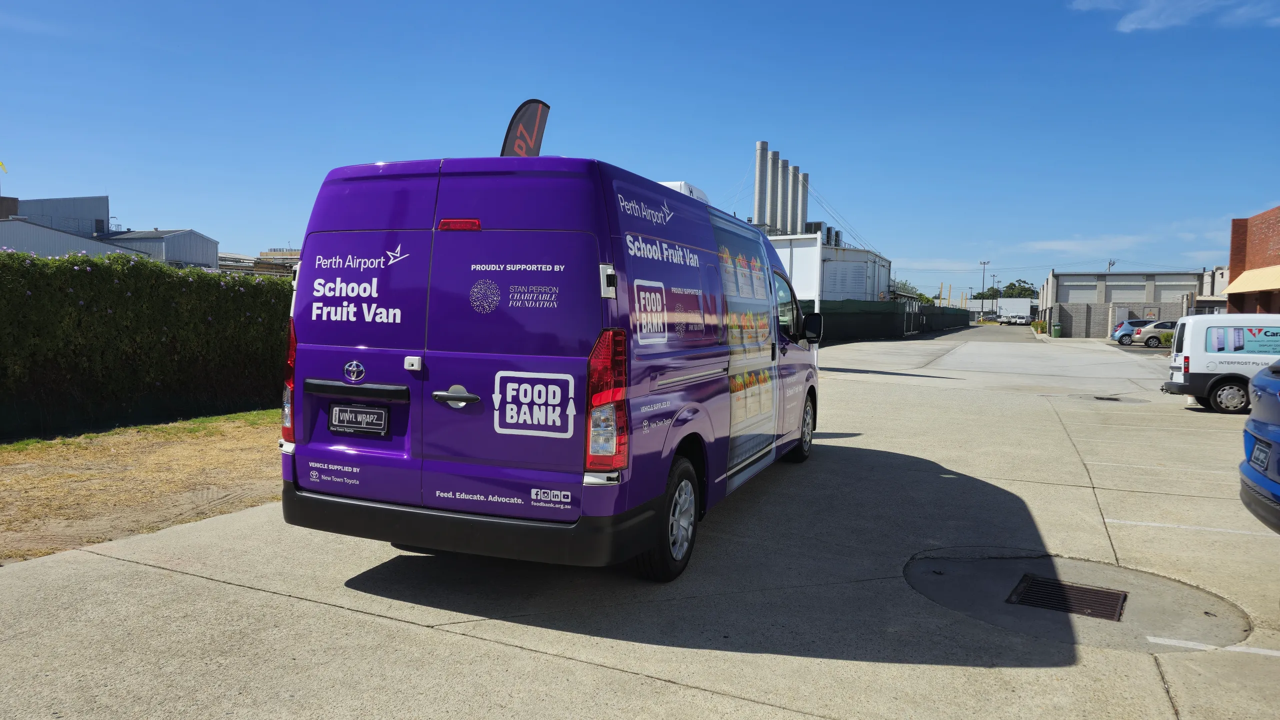 Purple Foodbank School Fruit Van Toyota Hiace viewed from the rear quarter outside the workshop