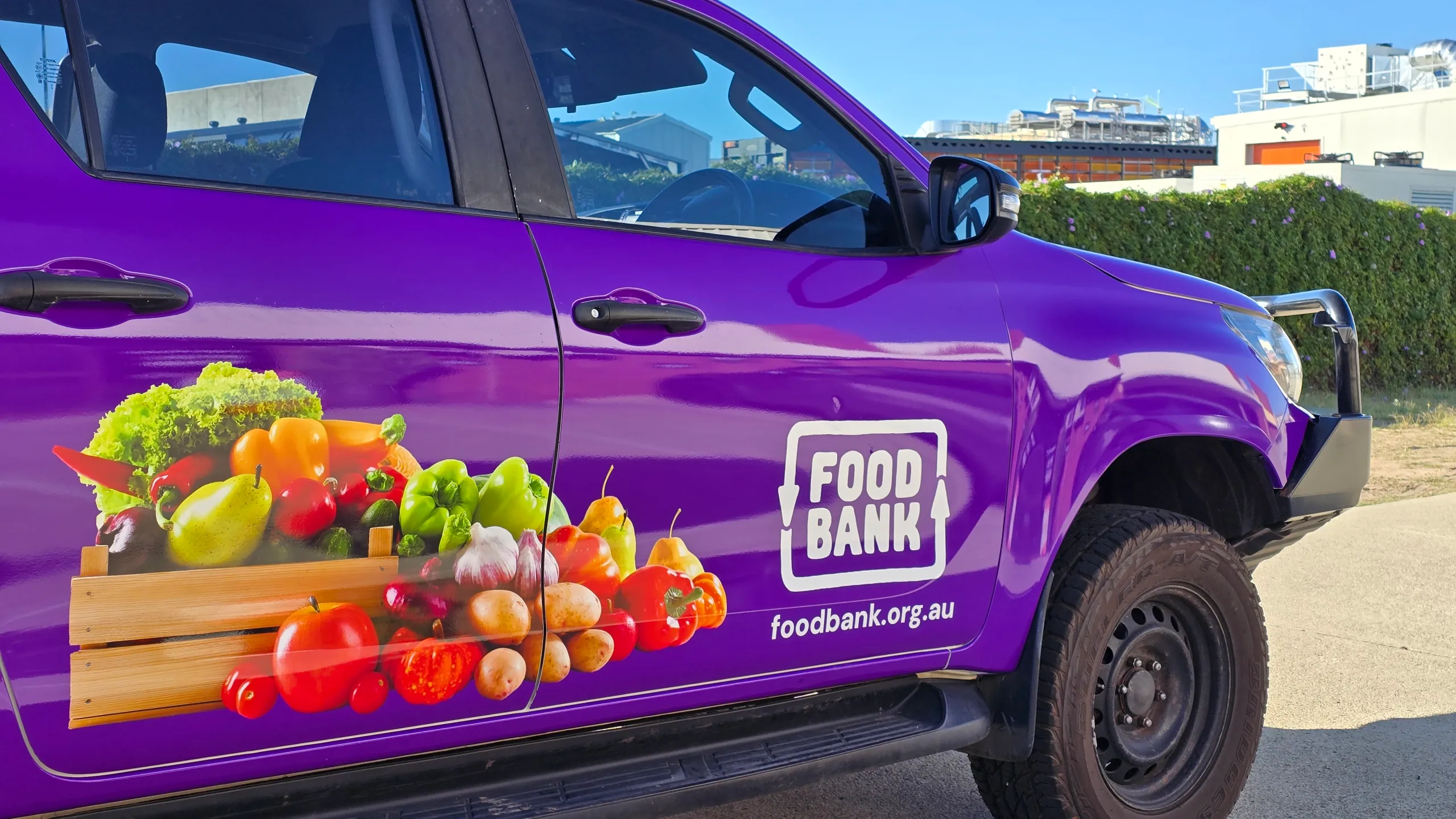 Foodbank logo and printed produce across the purple Toyota Hilux doors