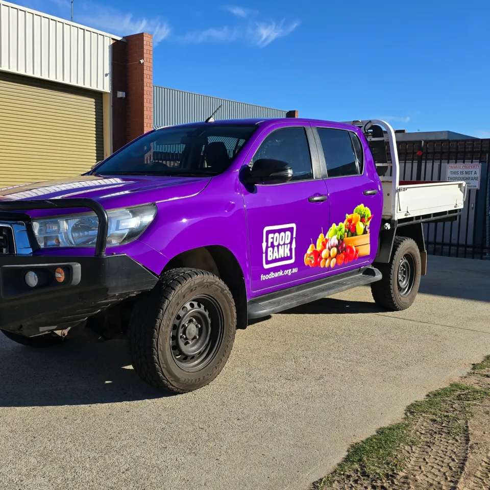 Toyota Hilux with purple Foodbank graphics and a black bull bar outdoors