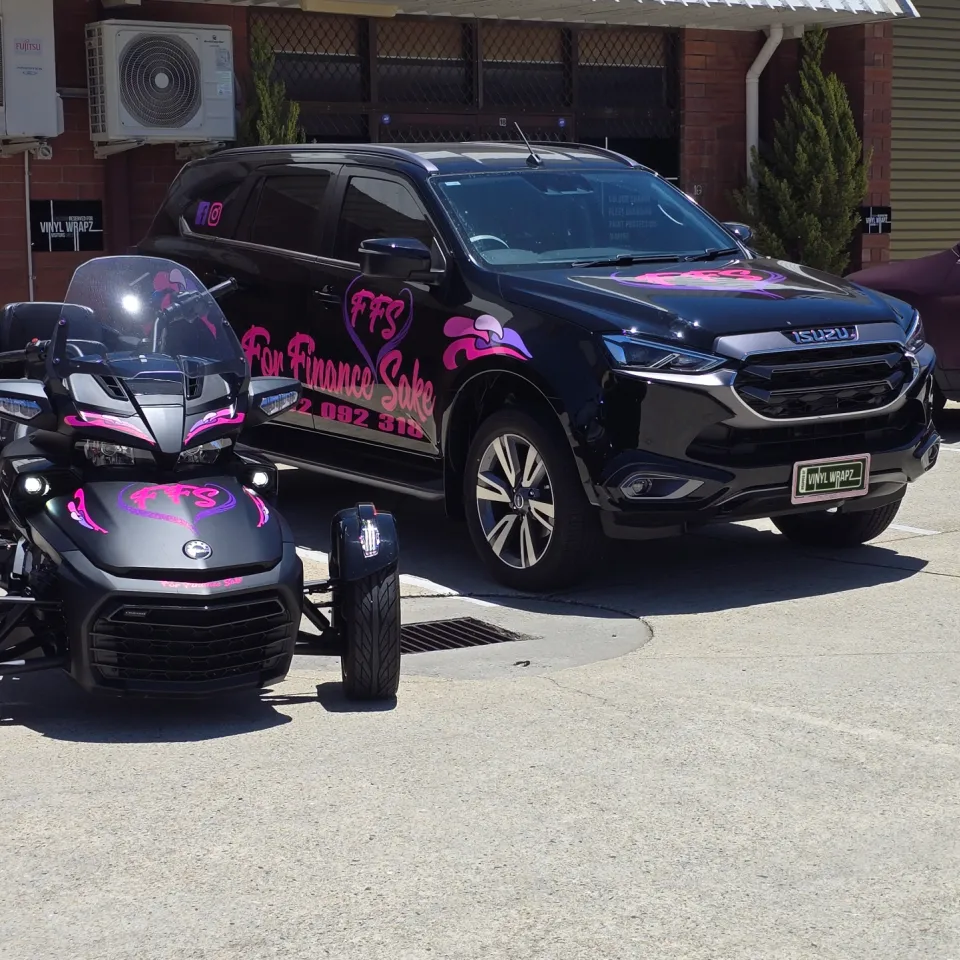 For Finance Sake Can-Am Spyder and Isuzu MU-X with matching pink graphics outside the workshop