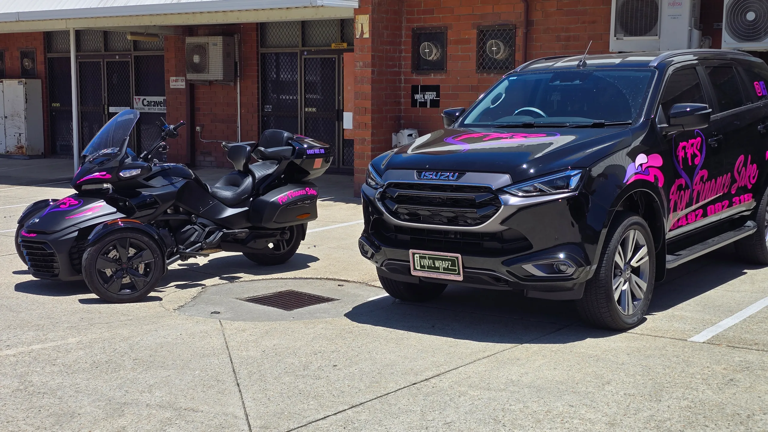Black Isuzu MU-X and Can-Am Spyder with matching pink For Finance Sake branding outdoors