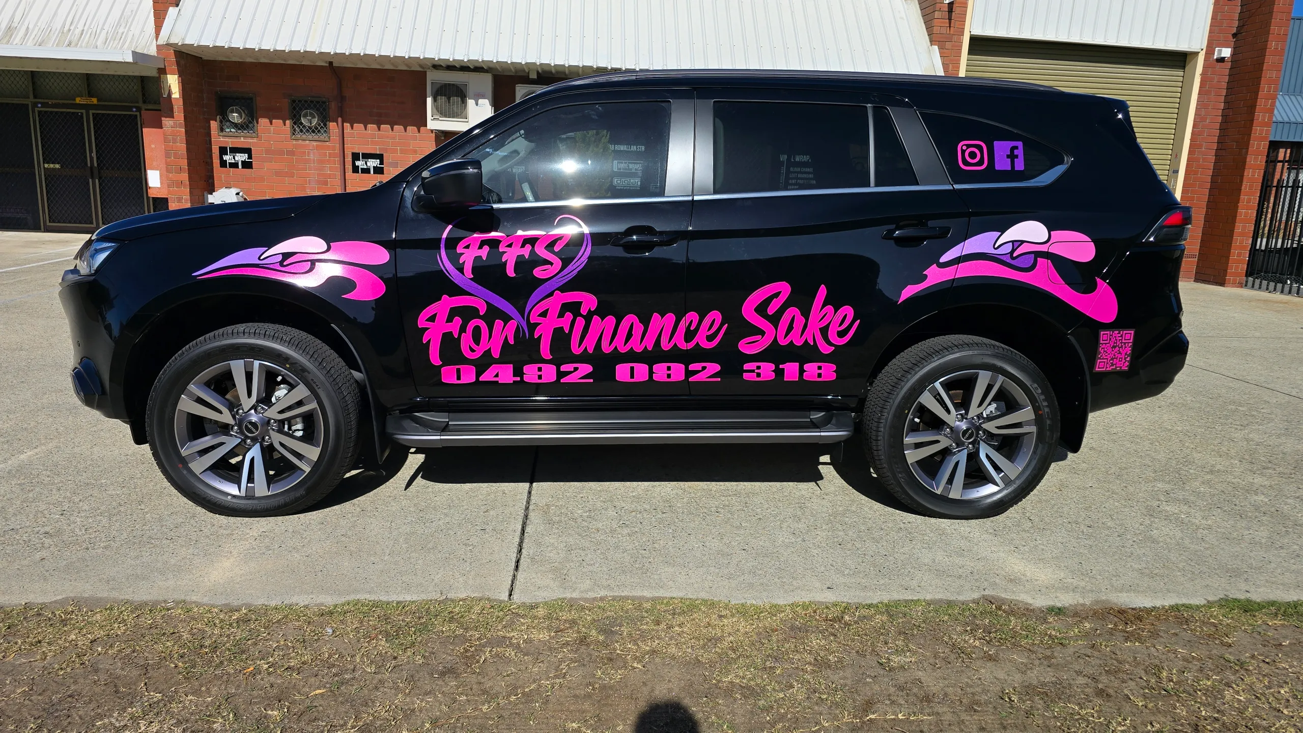 Pink For Finance Sake lettering across the side of a black Isuzu MU-X