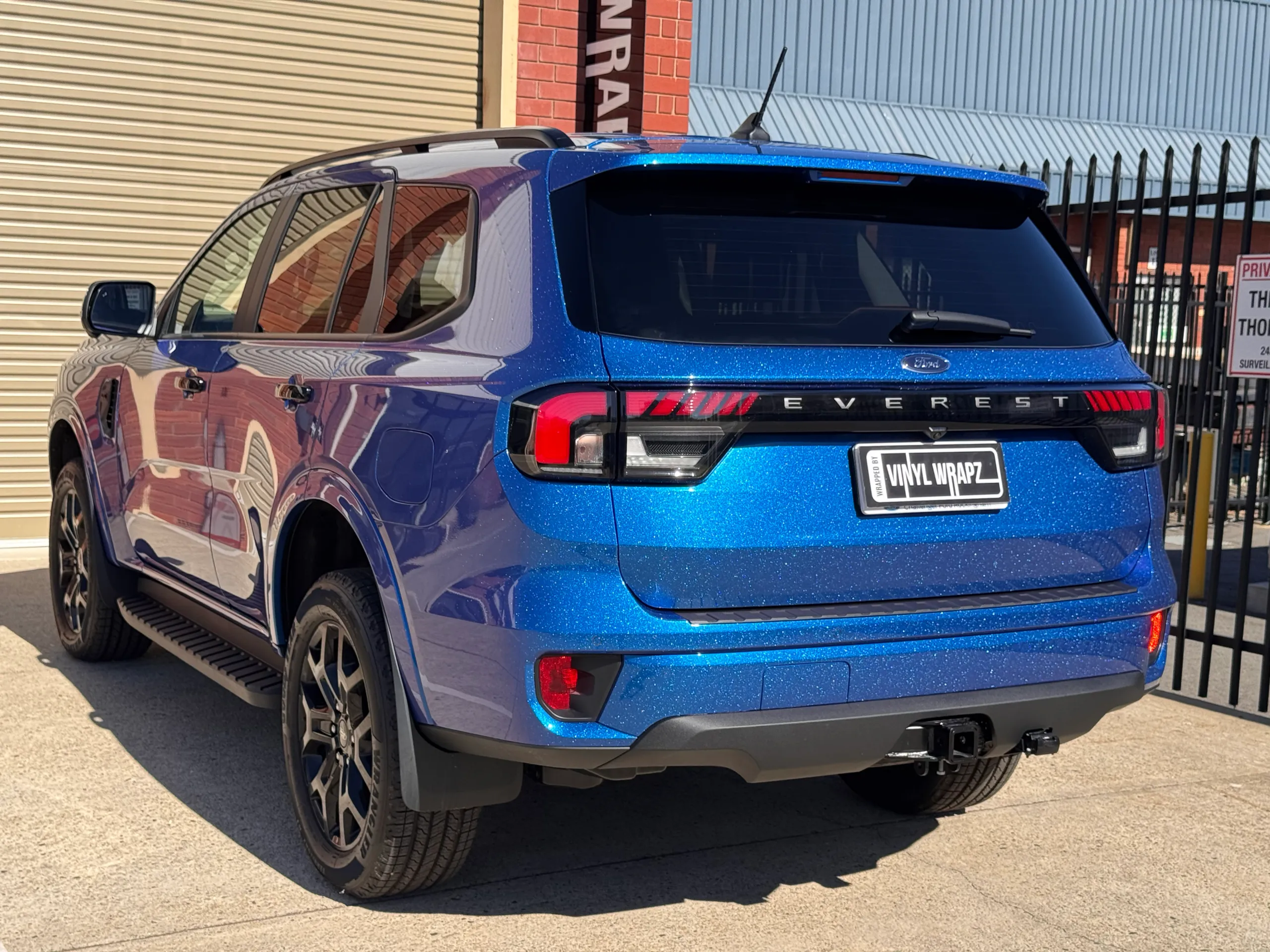 Iridescent blue Ford Everest viewed from the rear quarter outside the workshop