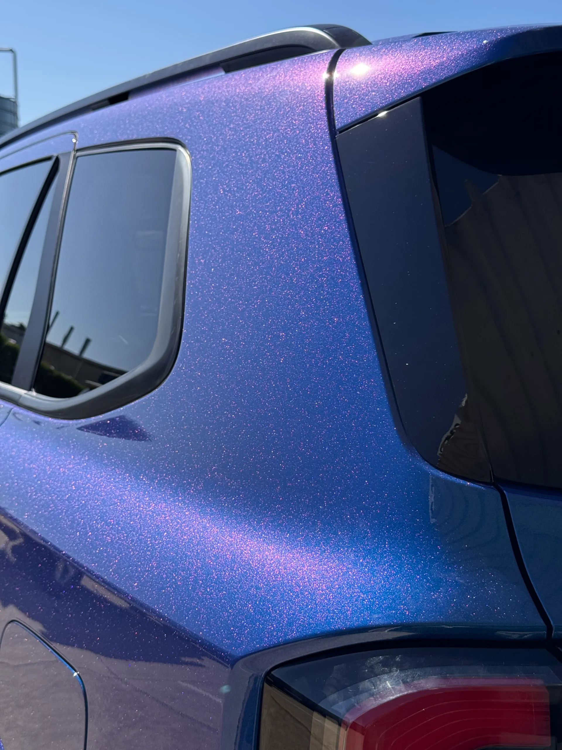 Purple highlights across the Ford Everest blue rear pillar beside its dark window