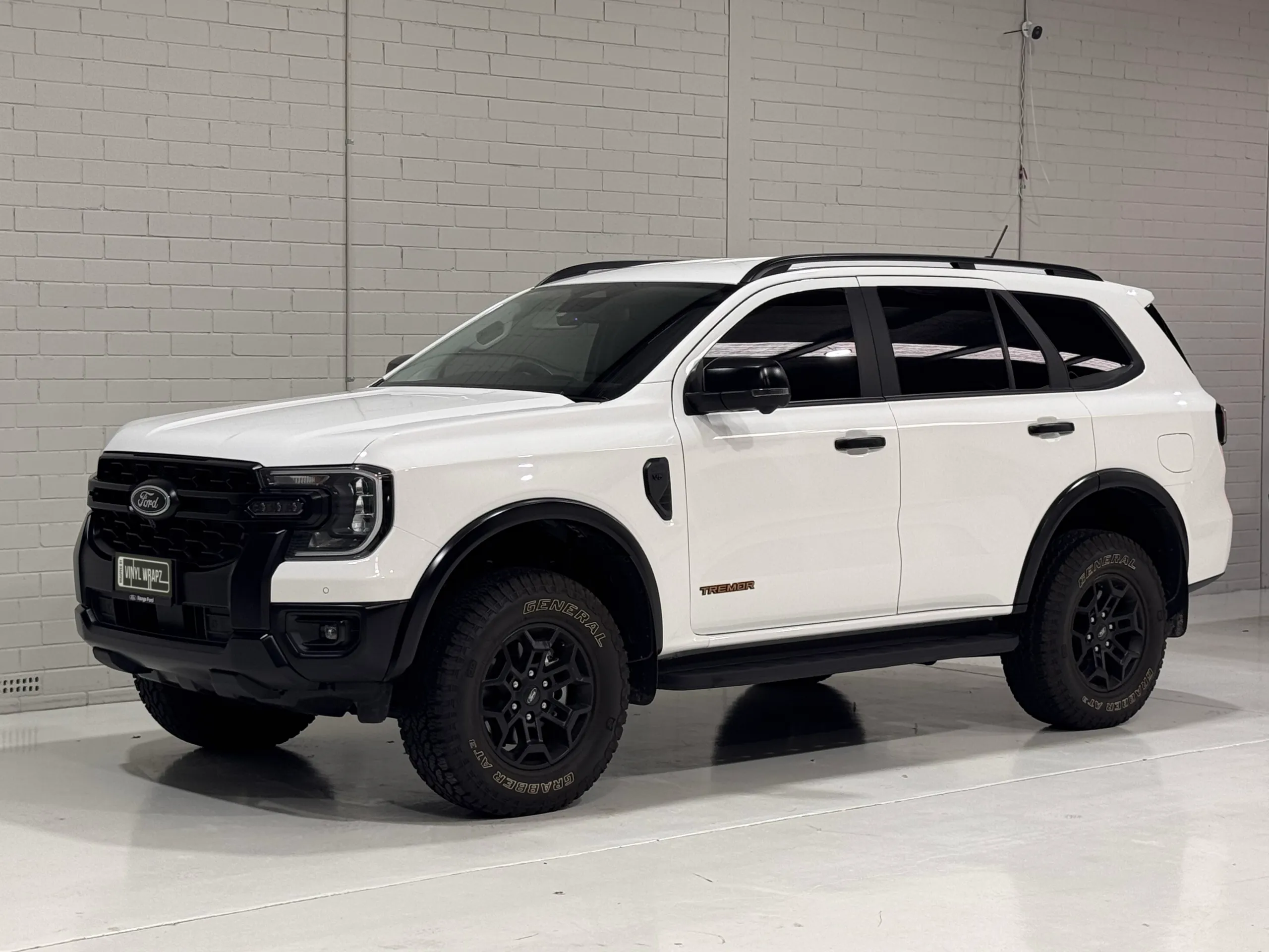 White Ford Everest Tremor viewed from the front quarter against a white workshop wall