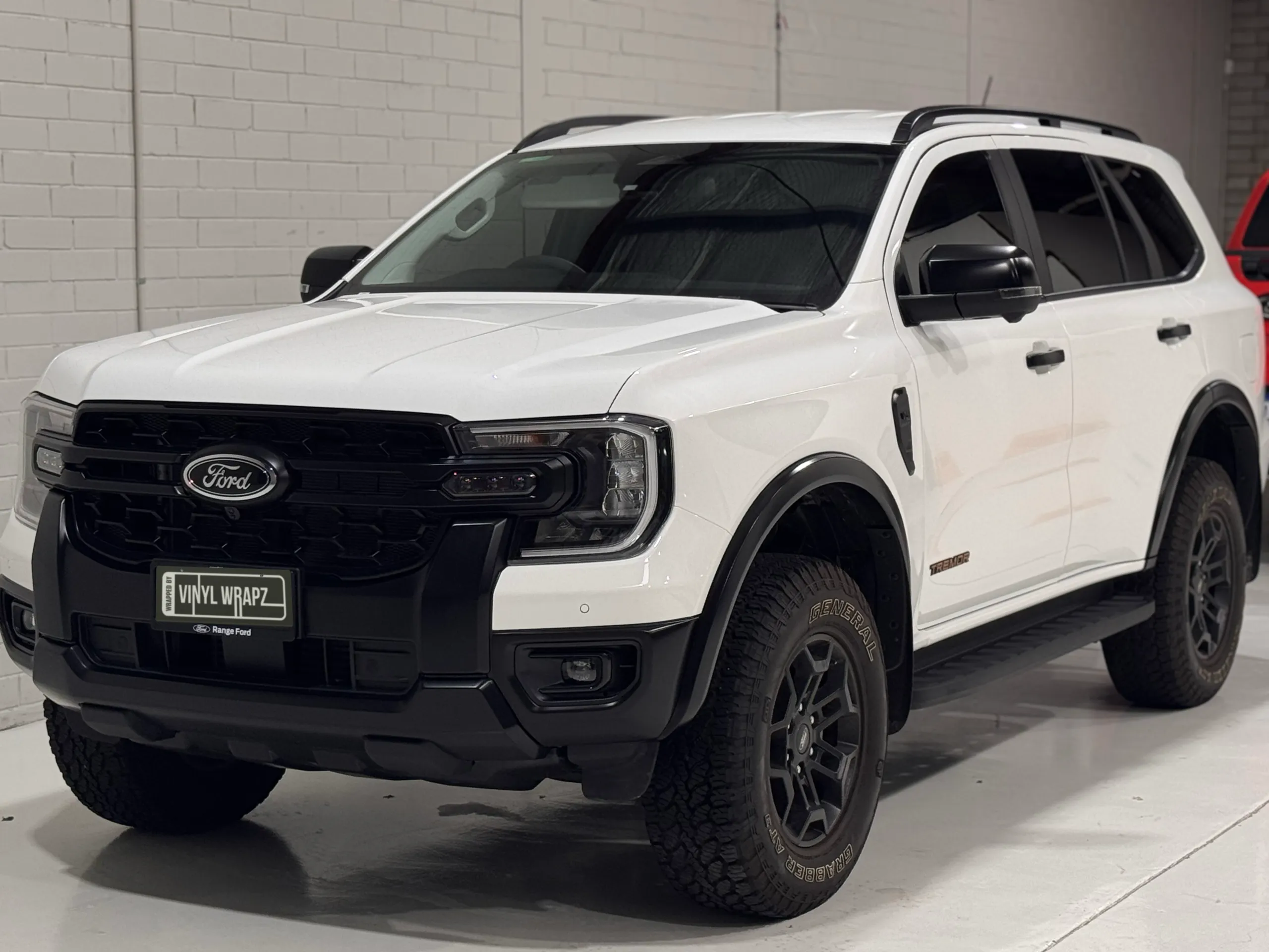 Front and side of a white Ford Everest Tremor, showing the black grille and wheels