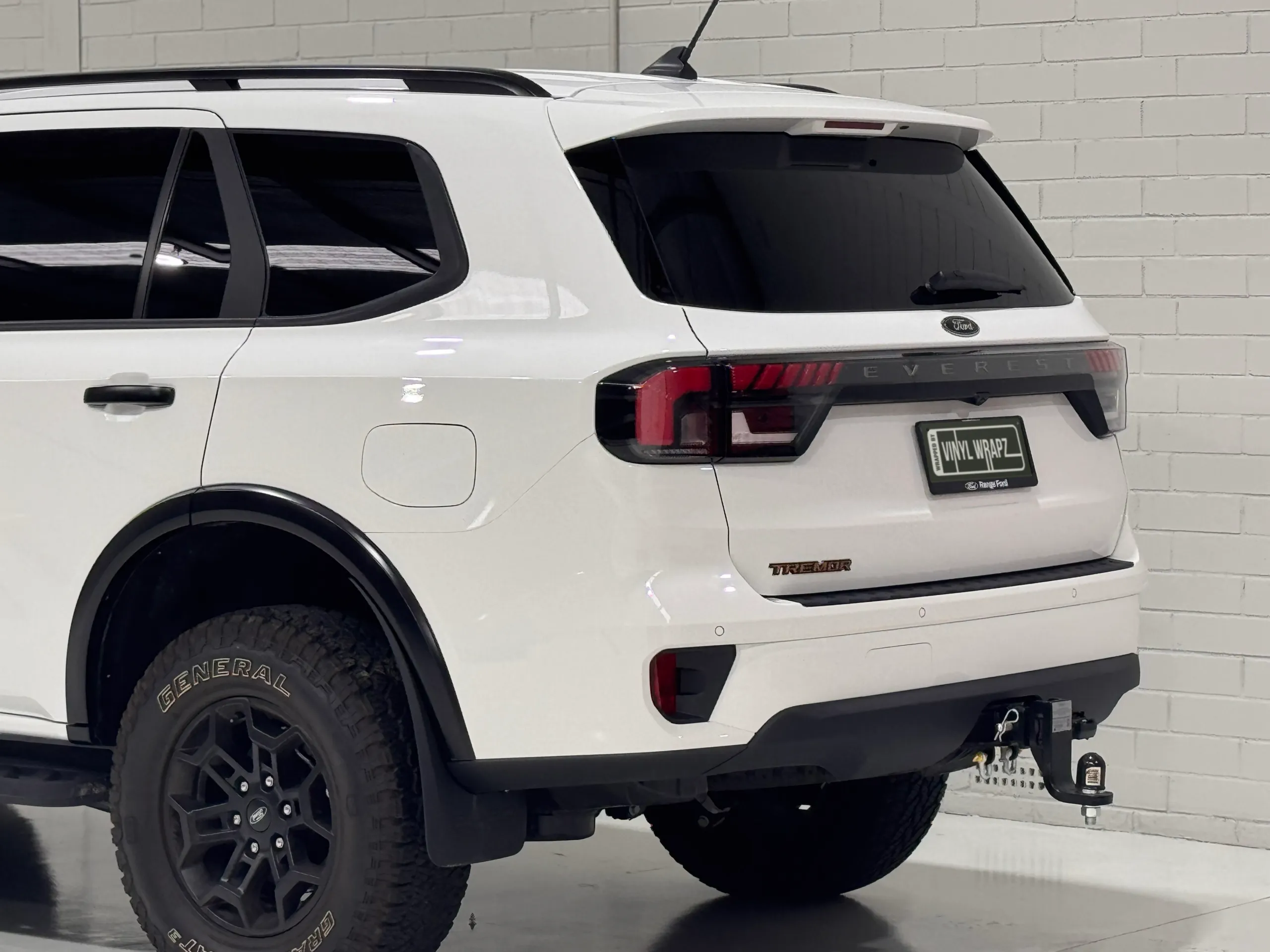Rear quarter of a white Ford Everest Tremor, showing the rear wheel, tailgate and tow bar