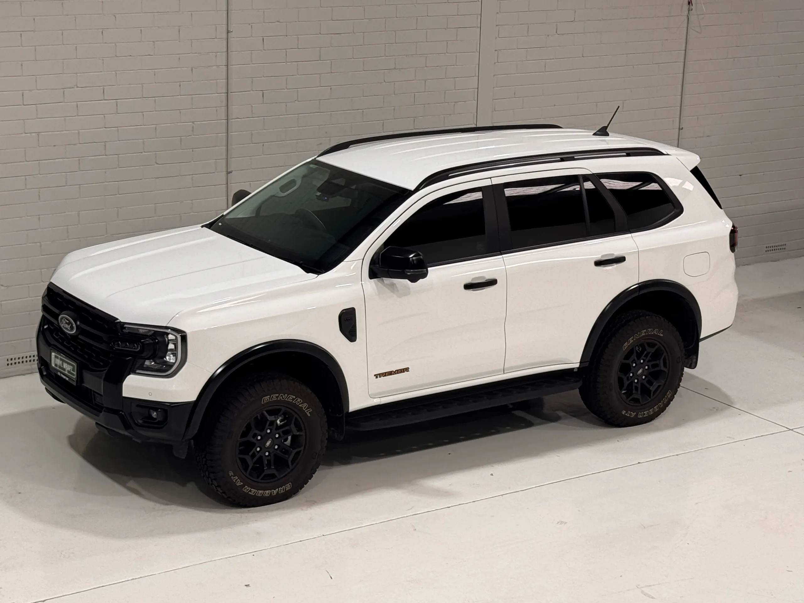 Elevated front-quarter view of a white Ford Everest Tremor in the workshop