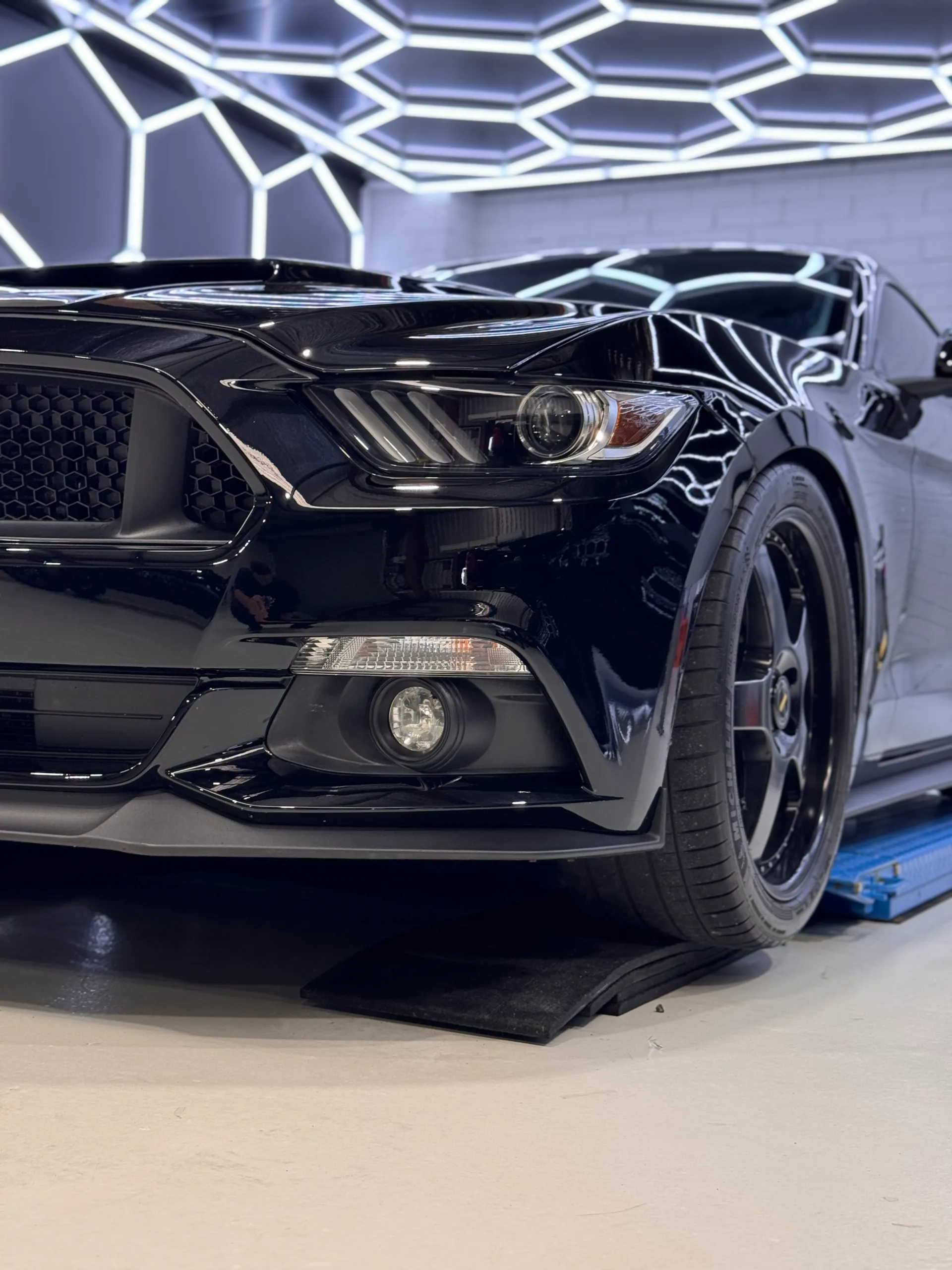 Low close view of the Ford Mustang headlight, front wheel and gloss black bumper