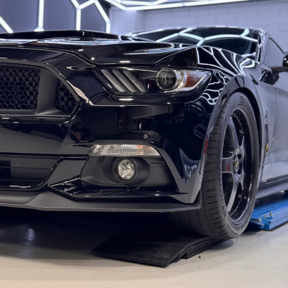Low close view of the Ford Mustang headlight, front wheel and gloss black bumper