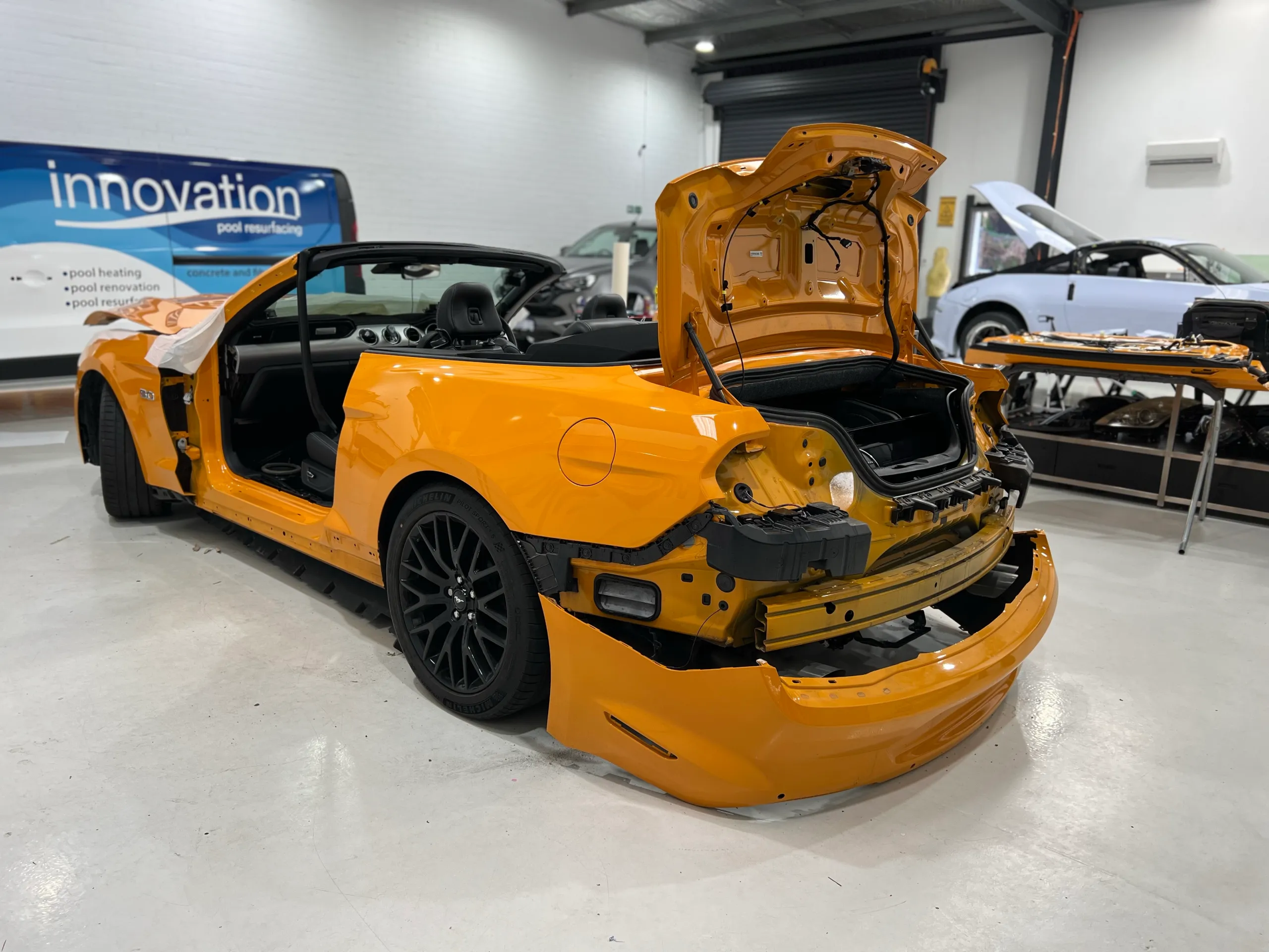 Orange Ford Mustang convertible dismantled for wrapping, rear quarter with boot open