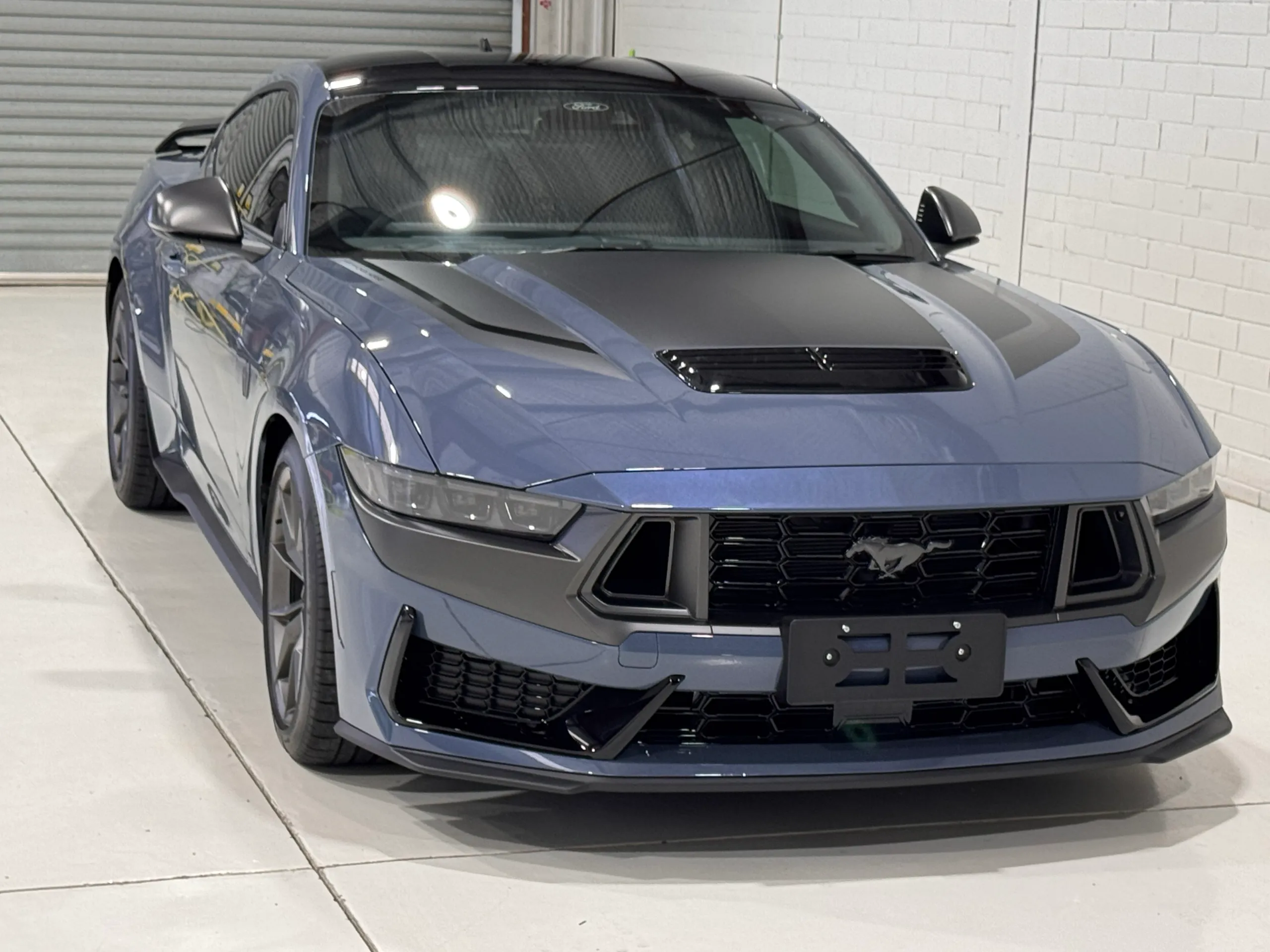 Front-quarter view of a gloss blue-grey Ford Mustang Dark Horse with contrasting bonnet graphics