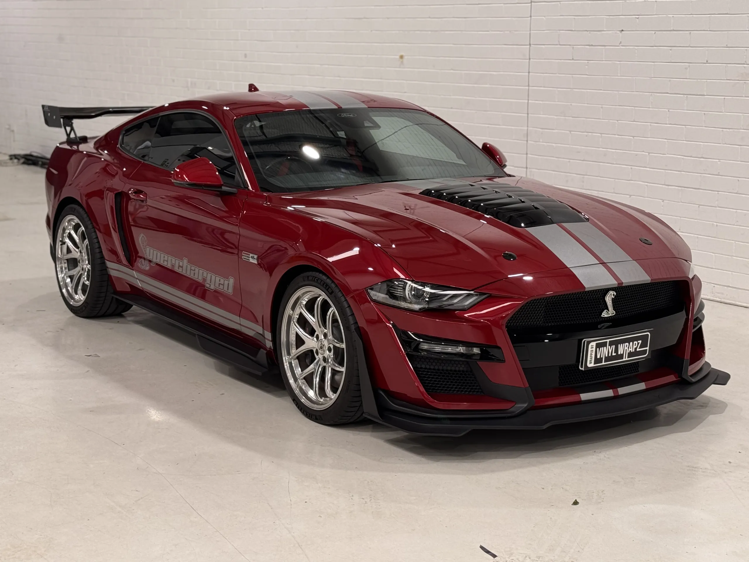 Red Ford Mustang with silver stripes, front quarter