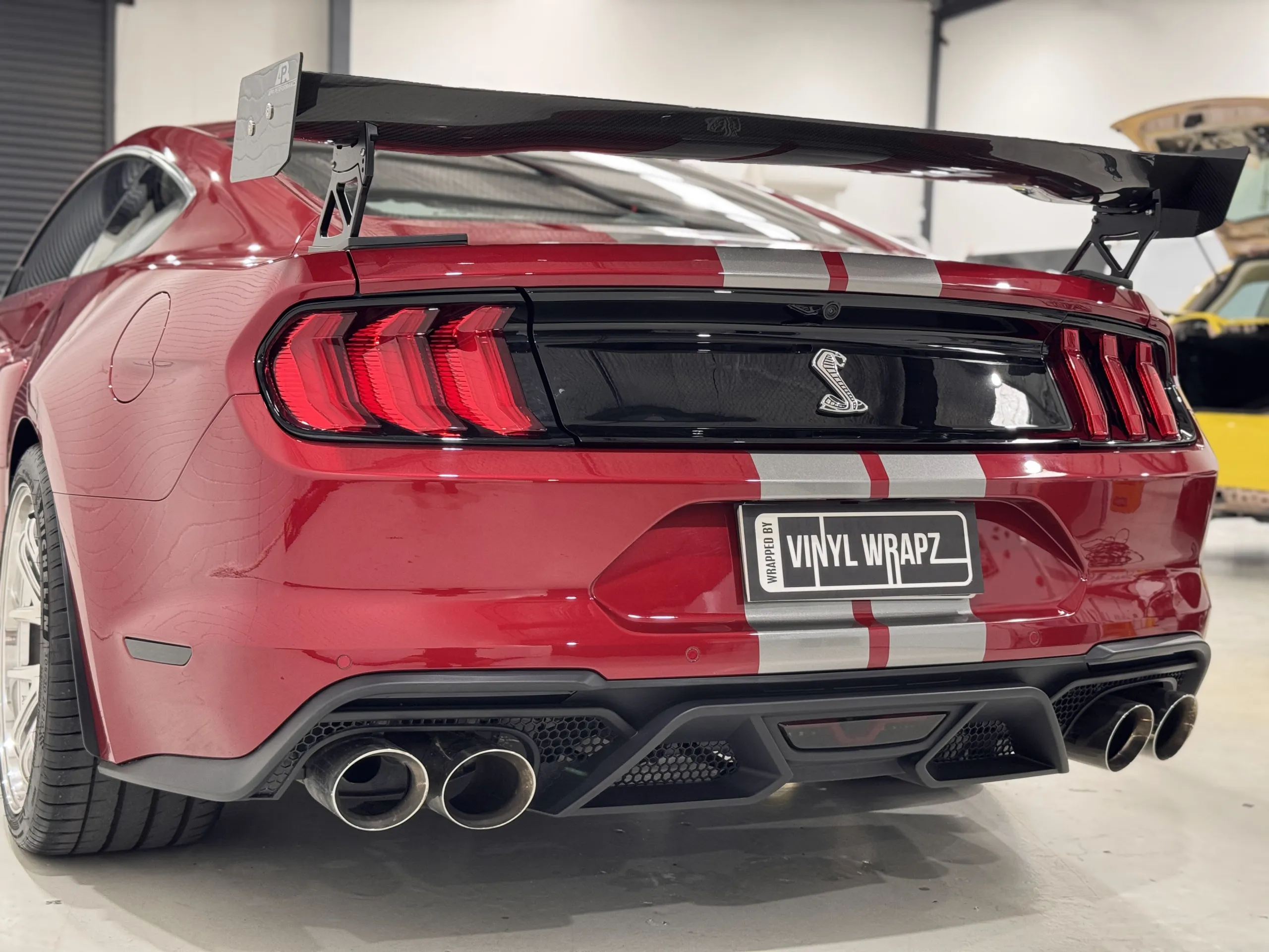 Red Ford Mustang with silver stripes, rear quarter