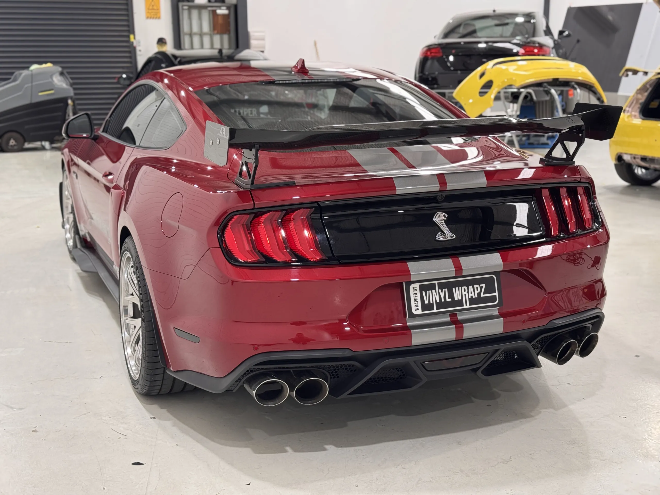Red Ford Mustang with silver stripes, rear quarter