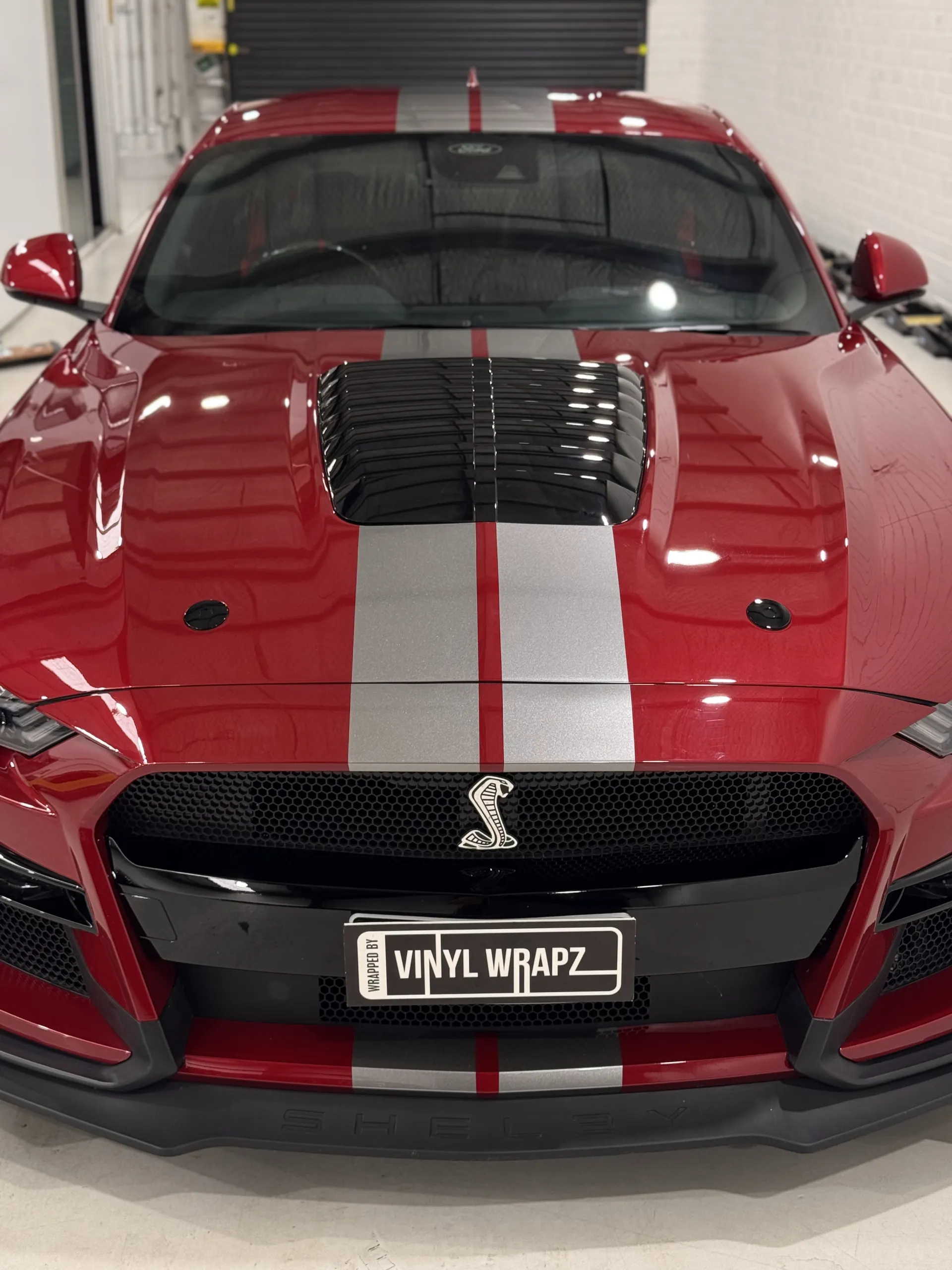 Red Ford Mustang with silver stripes, front