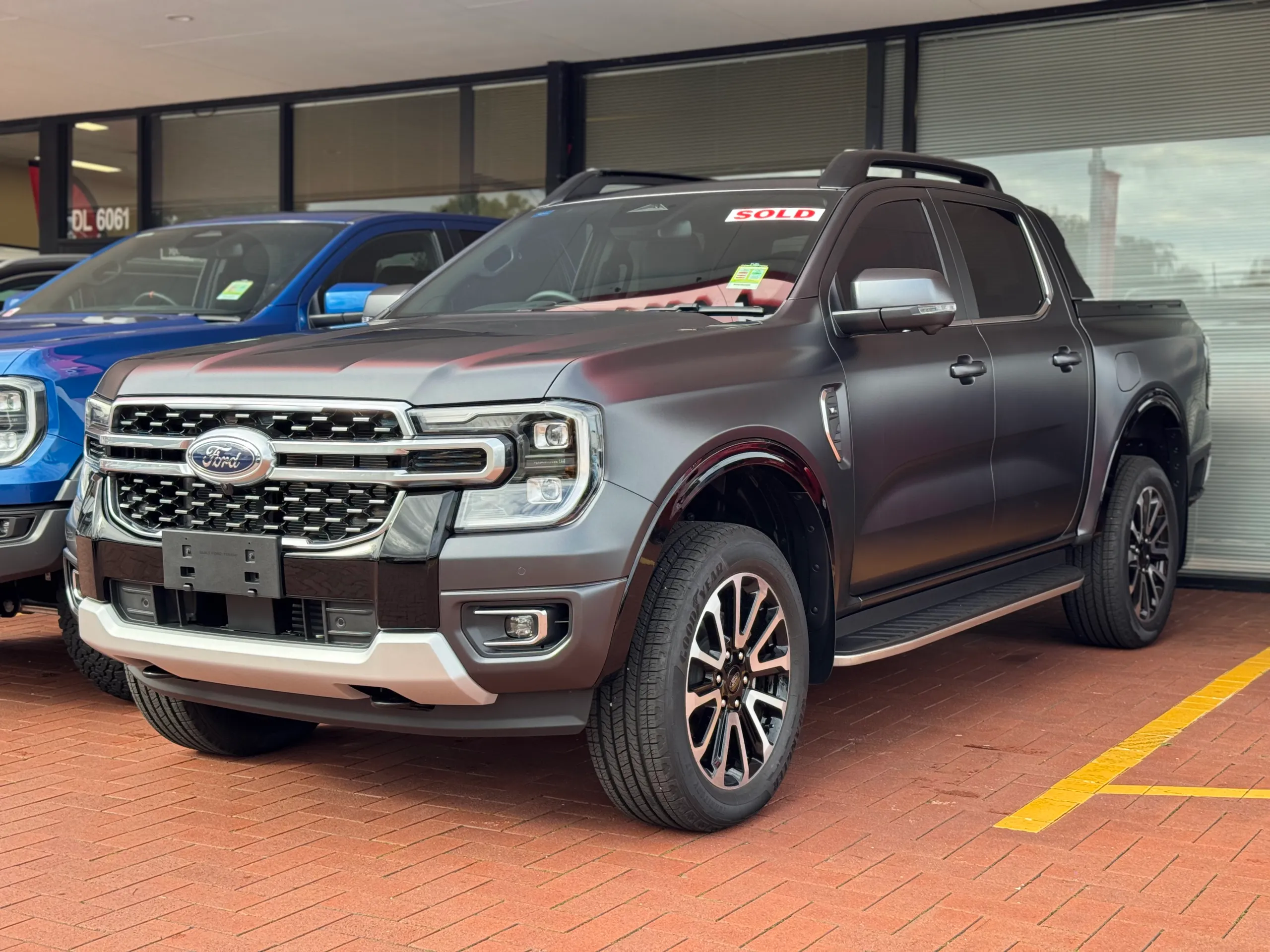Satin grey Ford Ranger Platinum viewed from the front quarter on a dealership forecourt