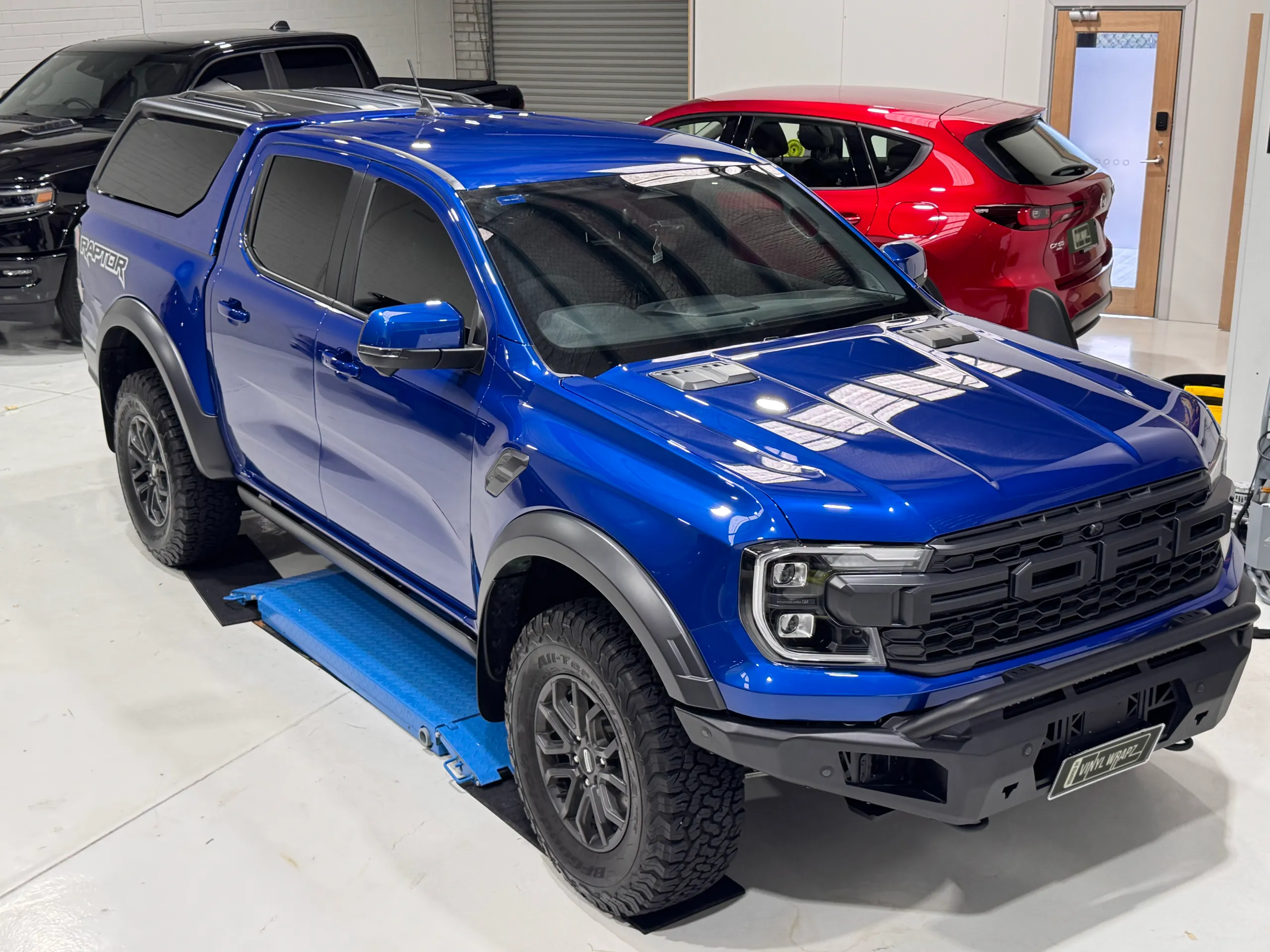 Gloss blue Ford Ranger Raptor viewed from above the front quarter in the workshop