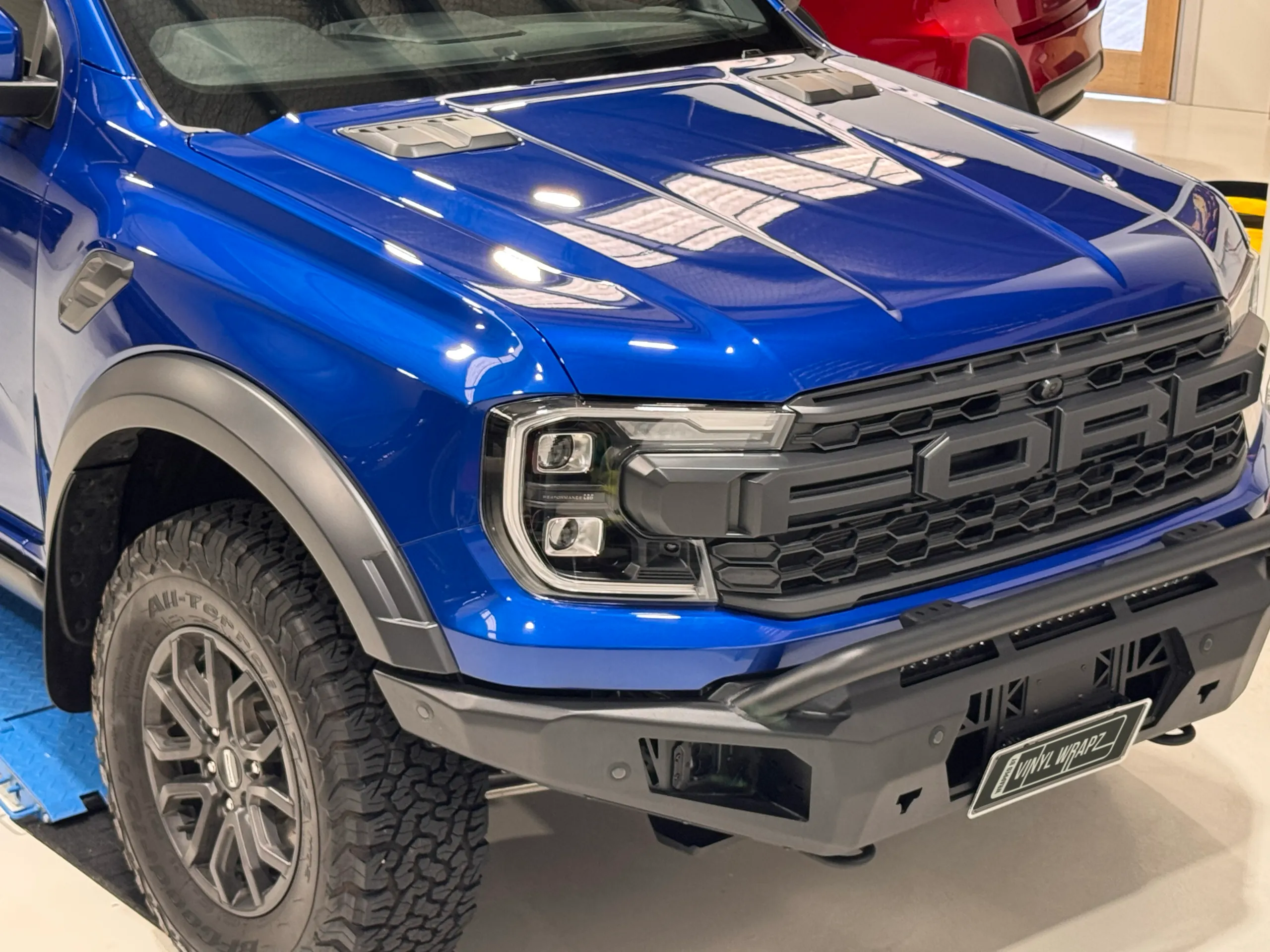 Blue Ford Ranger Raptor bonnet, grille and front bar reflecting workshop lights