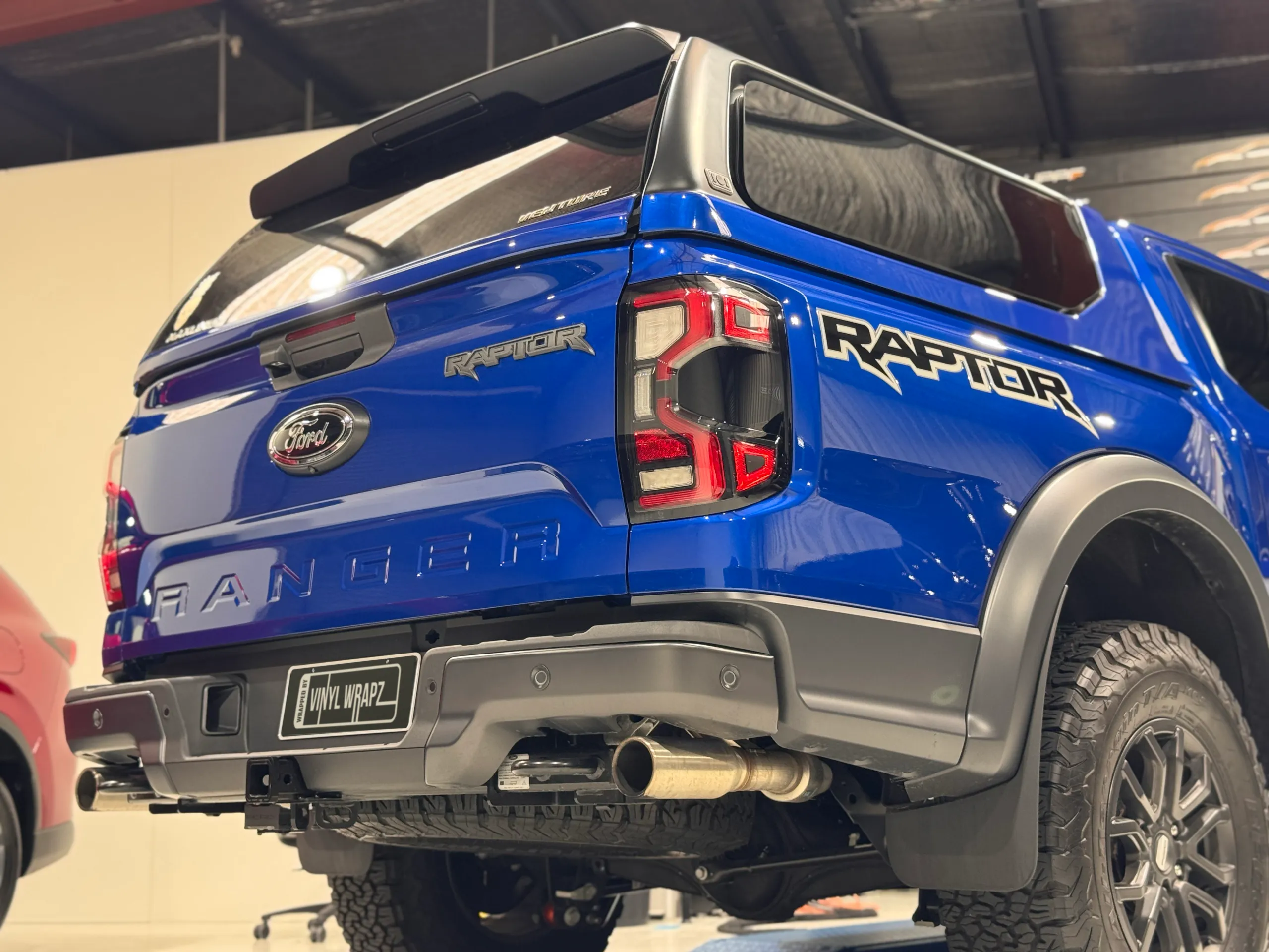 Low rear-quarter view of the gloss blue Ford Ranger Raptor with its canopy fitted