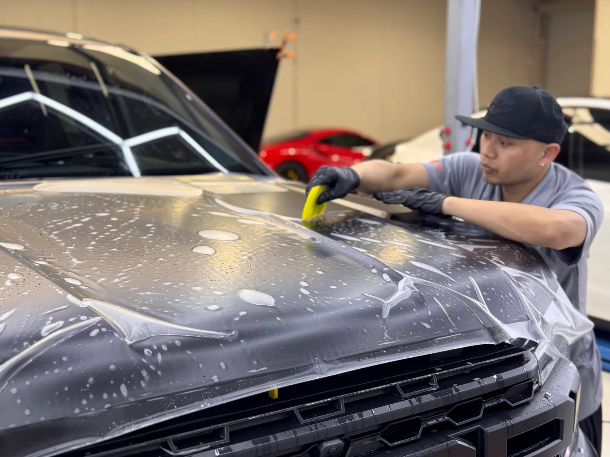 Installer smoothing wet film across the Ford Ranger Raptor bonnet with a squeegee