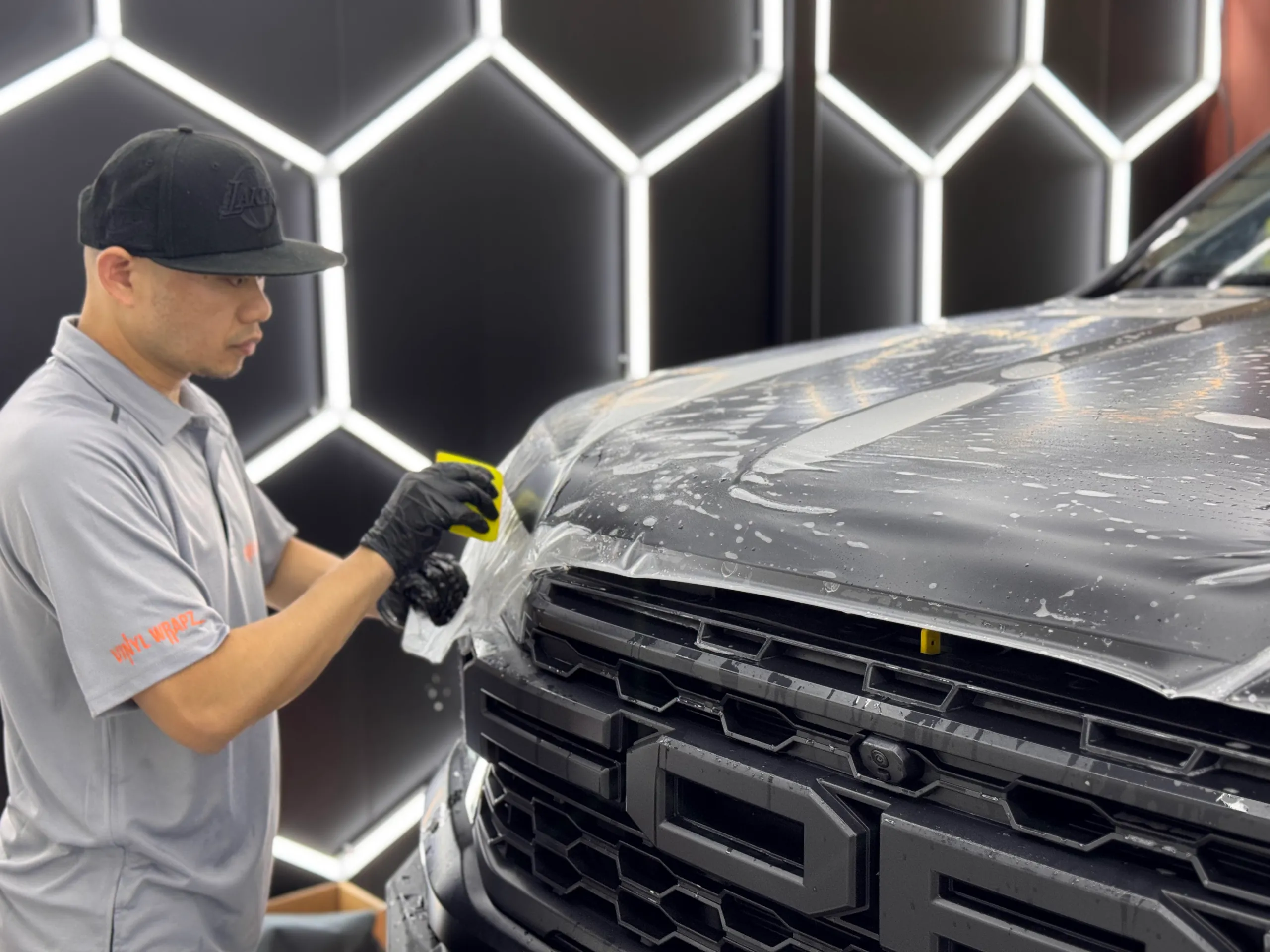 Installer working film around the Ranger Raptor bonnet edge above the grille