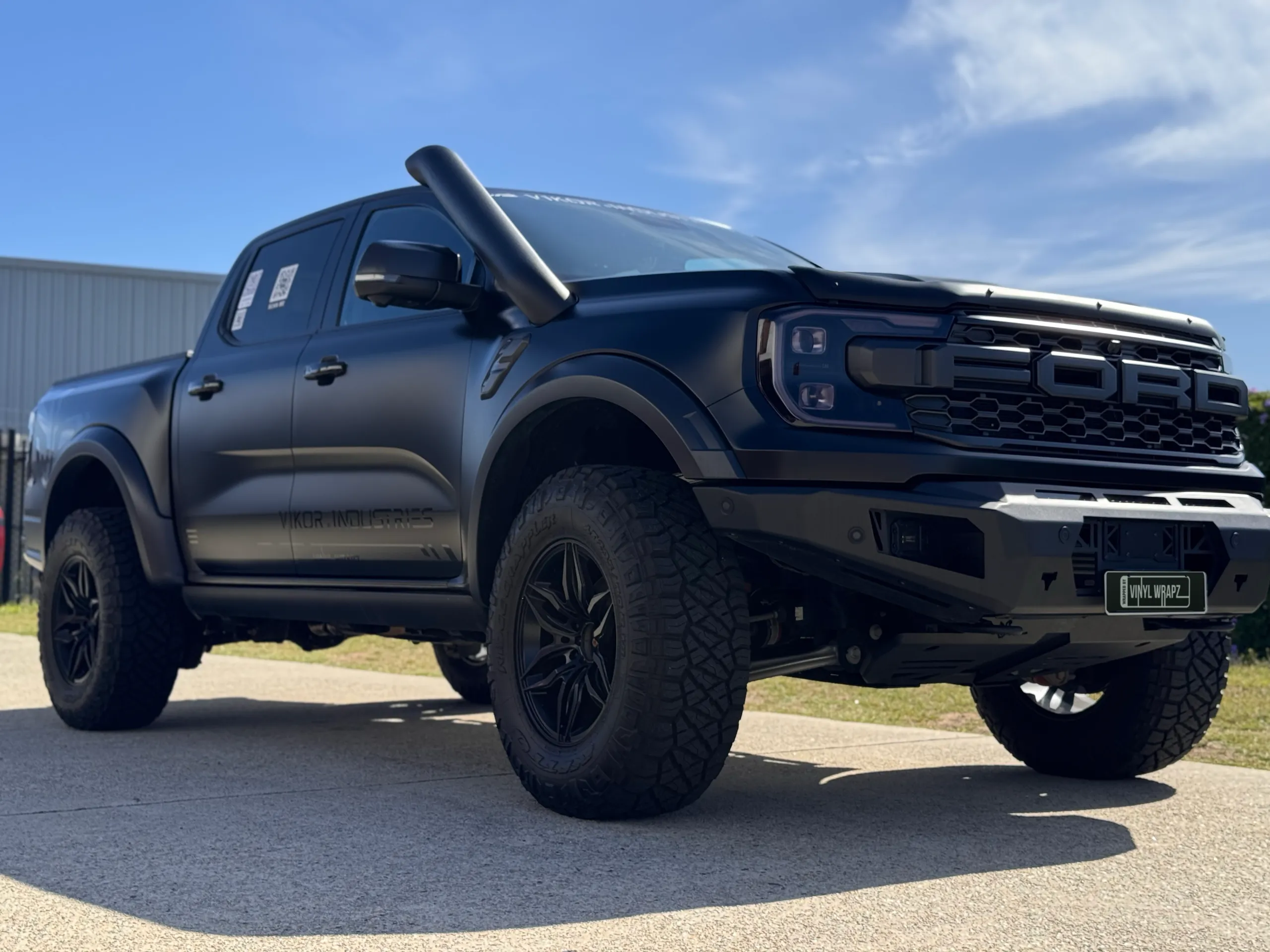 Satin grey Ranger Raptor viewed from a low front angle outside
