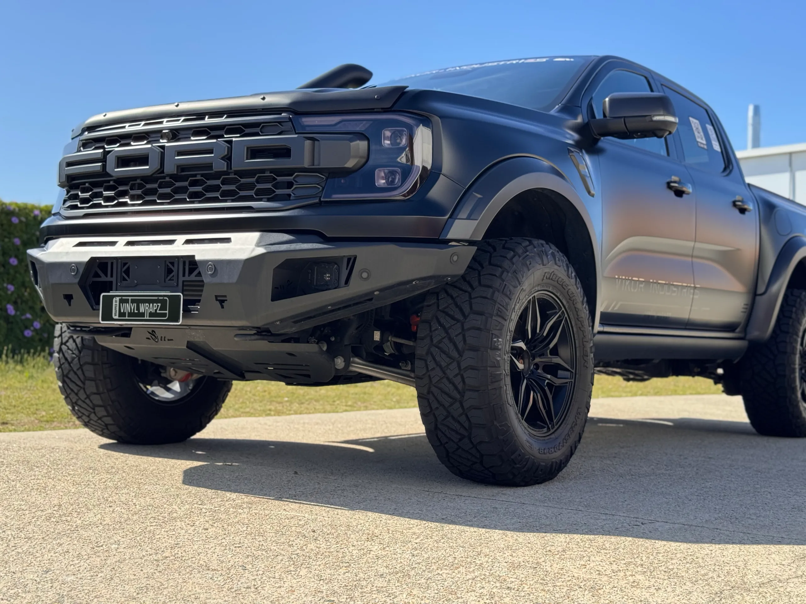 Low close view of the Ranger Raptor grille, bumper and front wheel outdoors